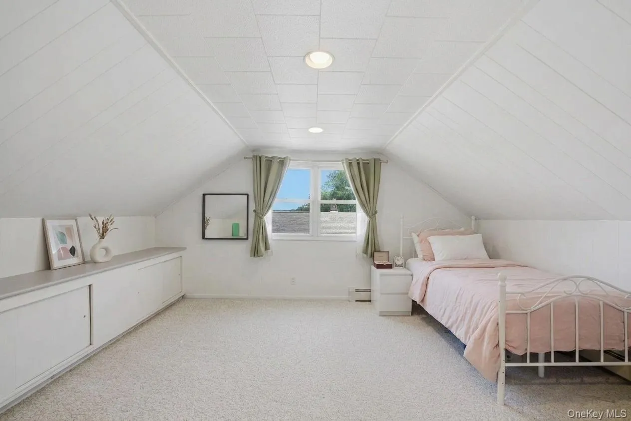 Attic bedroom with sloped paneled ceilings, recessed lighting, and light-toned carpeting Attic bedroom with sloped paneled ceilings, recessed lighting, and light-toned carpeting