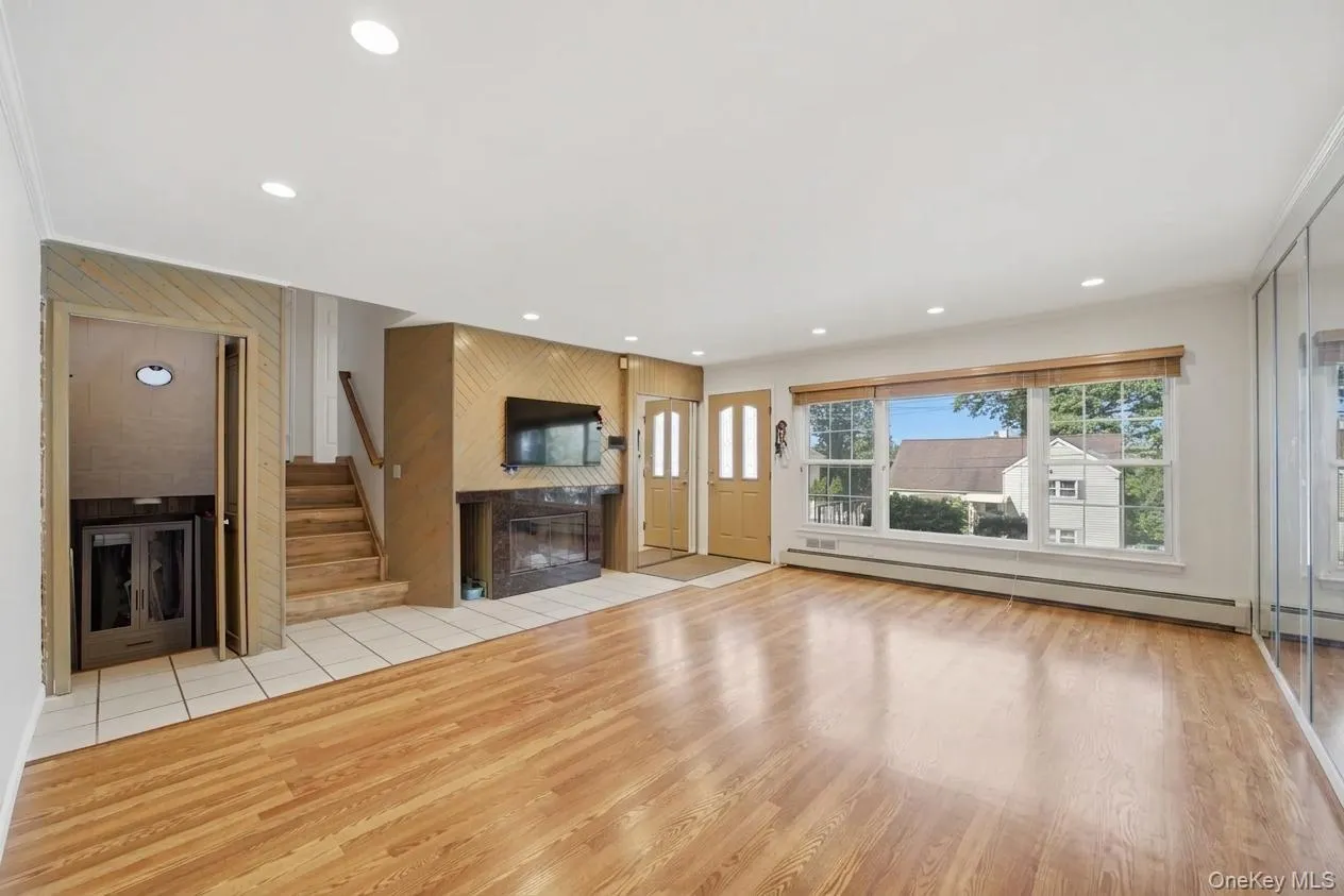 Spacious living area featuring wood-finish flooring, recessed lighting, and a large picture window Spacious living area featuring wood-finish flooring, recessed lighting, and a large picture window