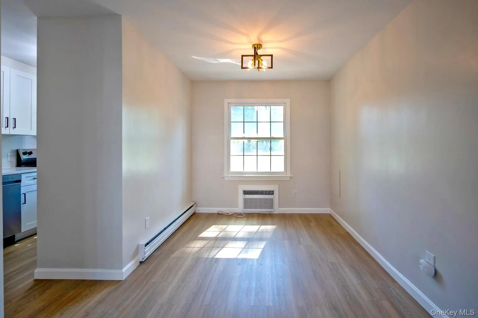 Bright interior space featuring wood-finish flooring, a double-hung window with grilles, and a window-mounted air conditioning unit Bright interior space featuring wood-finish flooring, a double-hung window with grilles, and a window-mounted air conditioning unit