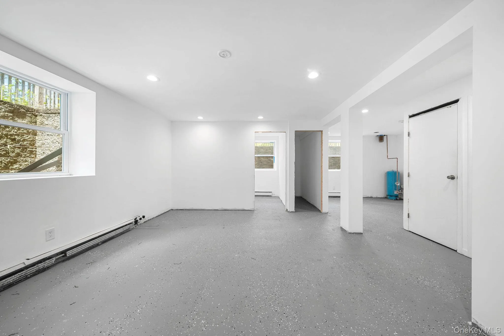 Finished lower level featuring recessed lighting, painted concrete flooring, multiple windows, and a white interior color palette Finished lower level featuring recessed lighting, painted concrete flooring, multiple windows, and a white interior color palette