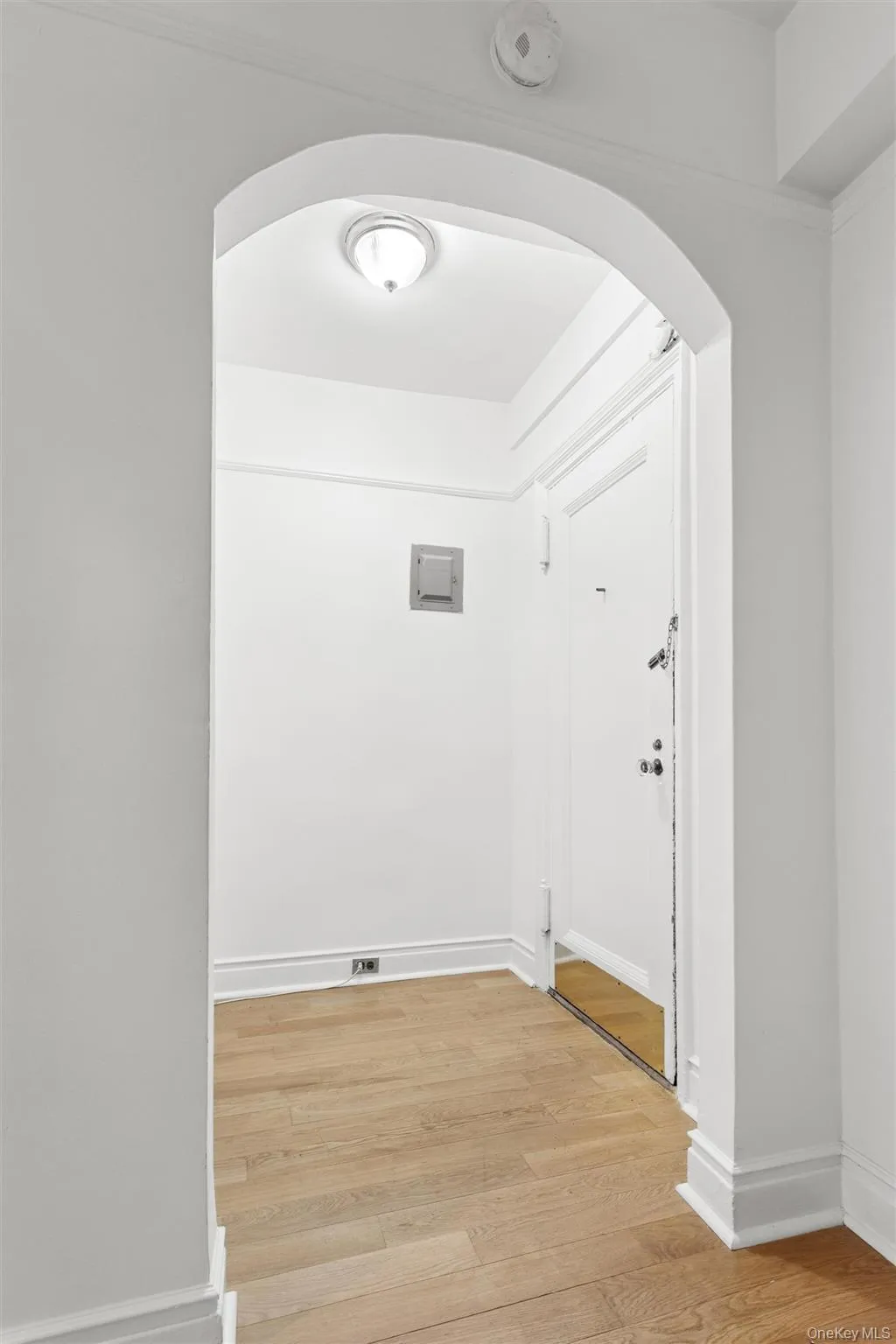 Foyer featuring an arched entryway, white oak 4" plank flooring, white baseboards, and a flush-mount ceiling light. Foyer featuring an arched entryway, white oak 4" plank flooring, white baseboards, and a flush-mount ceiling light.