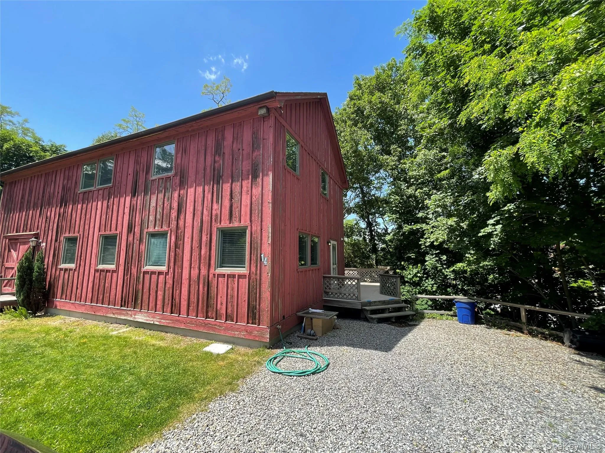 View of home's exterior with a deck, a lawn, and board and batten siding View of home's exterior with a deck, a lawn, and board and batten siding