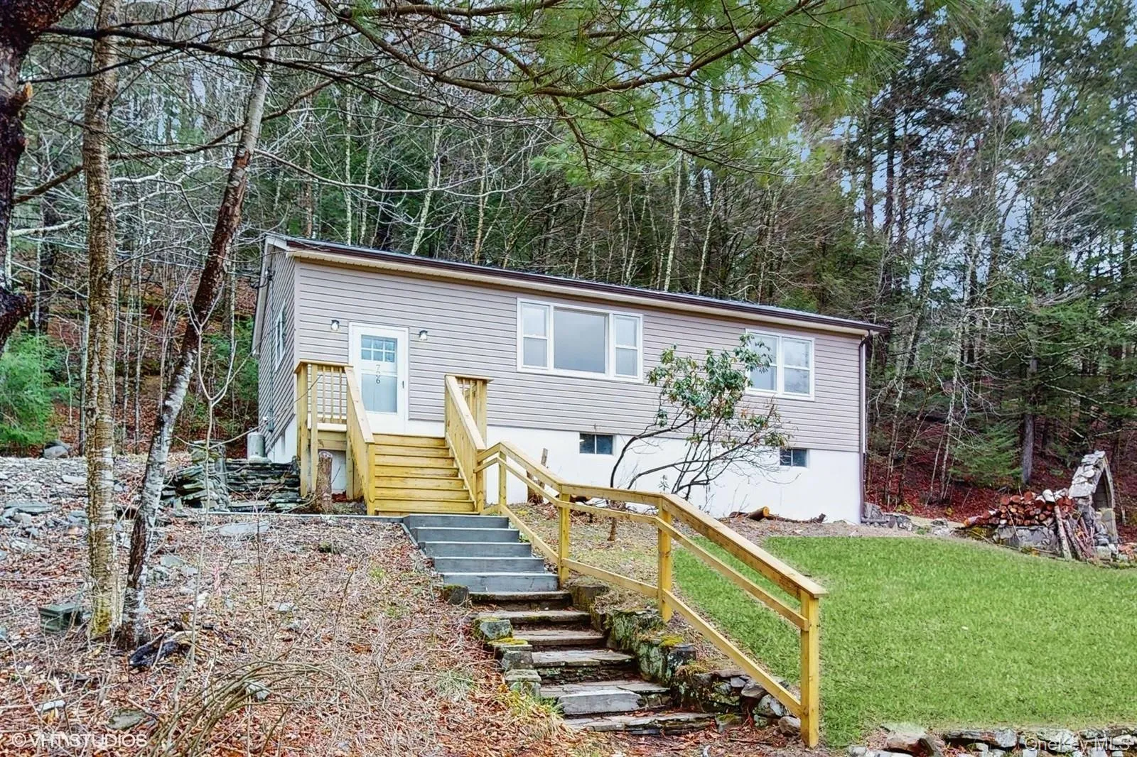 featuring a front lawn, stairway, and a forest view featuring a front lawn, stairway, and a forest view