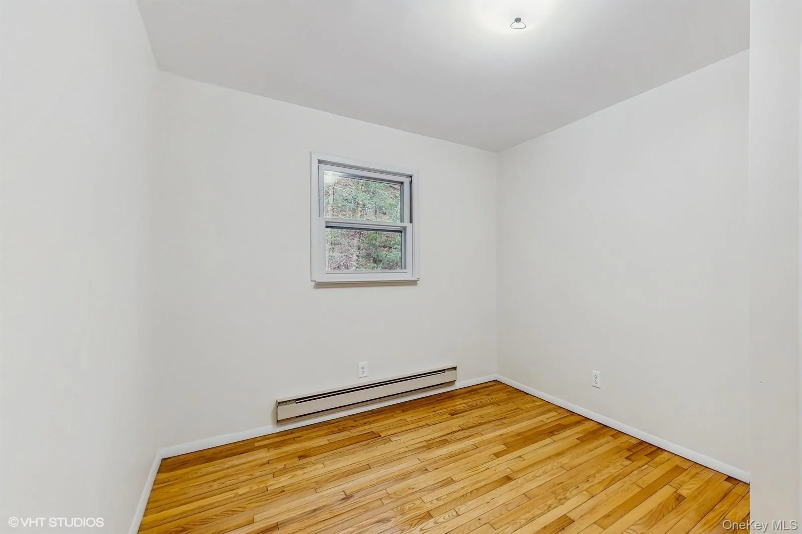 Room with light wood-style floors, baseboards, and a baseboard heating unit Room with light wood-style floors, baseboards, and a baseboard heating unit