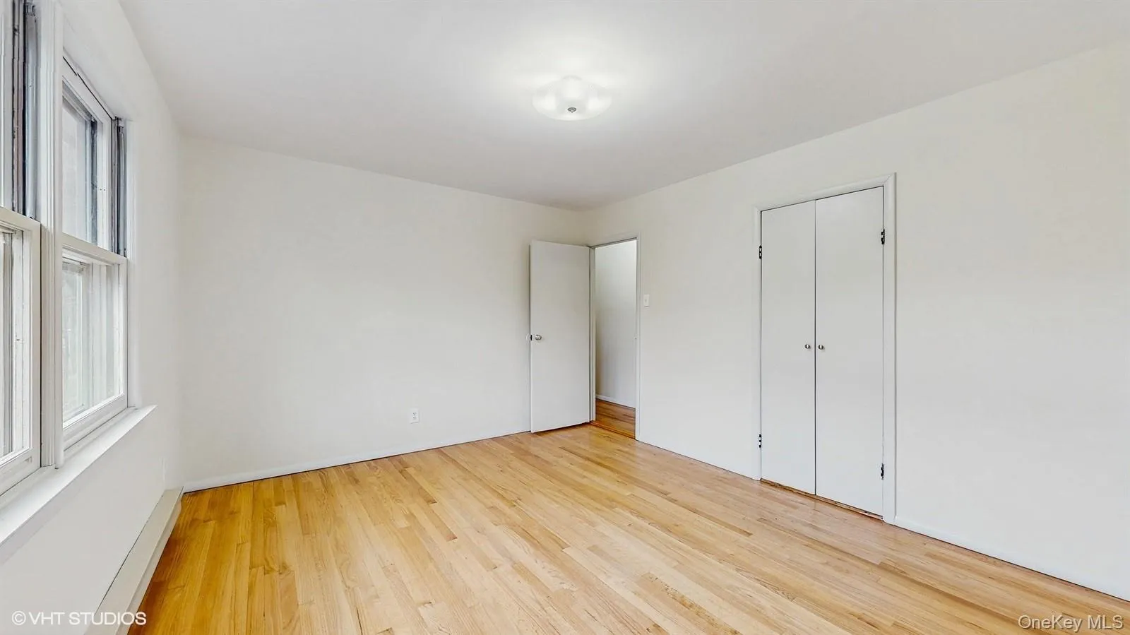 Primary bedroom with multiple windows wood finished floors Primary bedroom with multiple windows wood finished floors