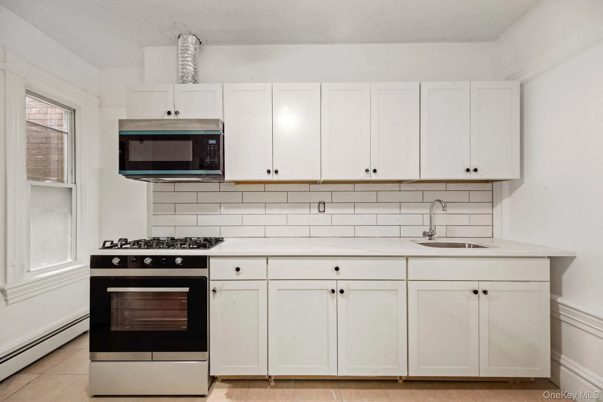 Bright and updated kitchen featuring white shaker cabinetry, subway tile backsplash, quartz-style countertops, and stainless steel appliances. Bright and updated kitchen featuring white shaker cabinetry, subway tile backsplash, quartz-style countertops, and stainless steel appliances.