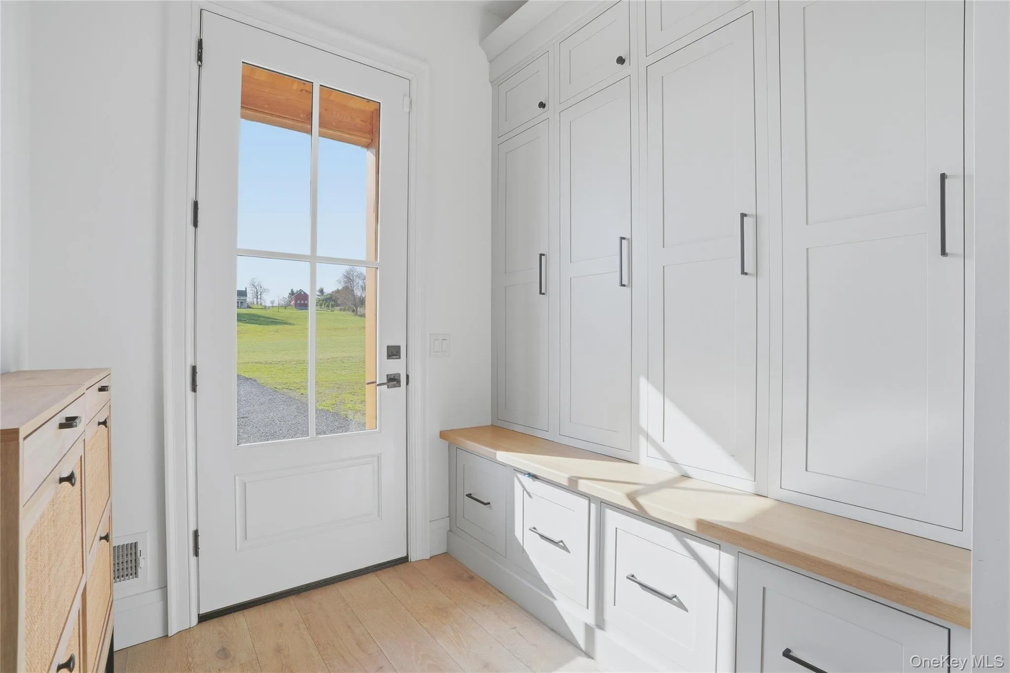 Entryway mudroom featuring white shaker-style cabinetry, wood-finish countertops, and light wood-finish flooring Entryway mudroom featuring white shaker-style cabinetry, wood-finish countertops, and light wood-finish flooring
