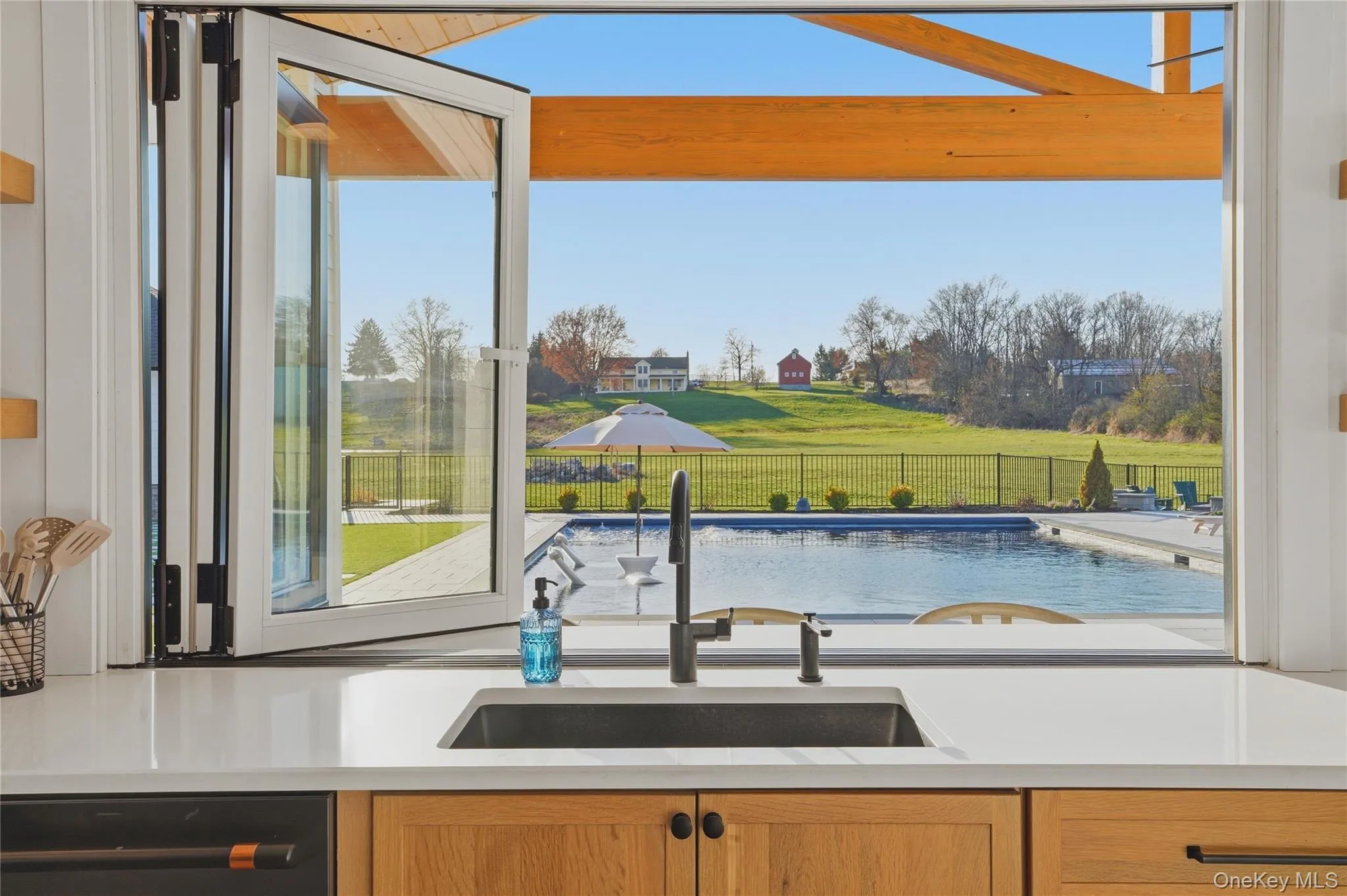 Bi-fold window opening to an outdoor pool area with a wrought iron fence Bi-fold window opening to an outdoor pool area with a wrought iron fence