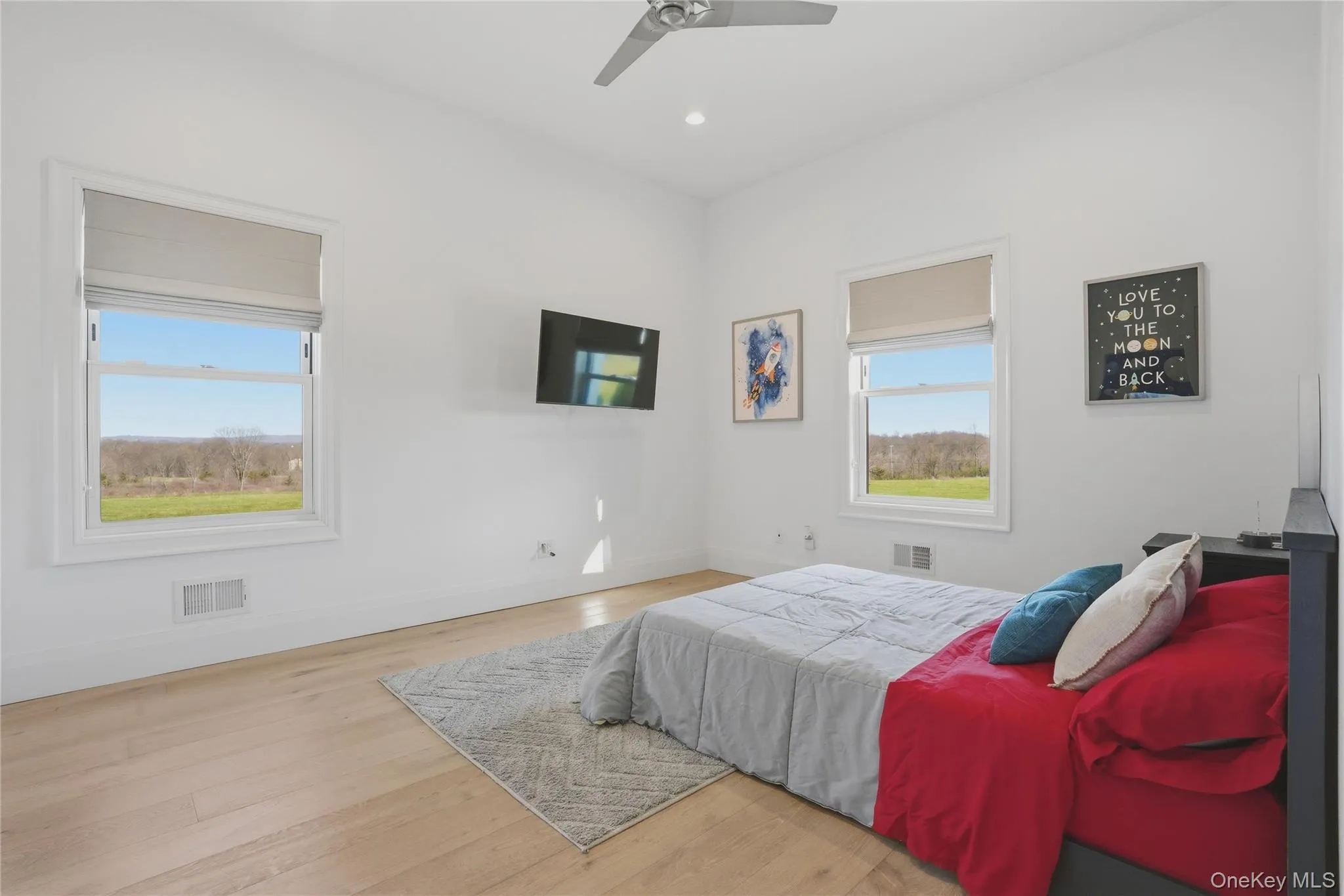 Bright room featuring two large windows, wood-finish flooring, a ceiling fan, and recessed lighting Bright room featuring two large windows, wood-finish flooring, a ceiling fan, and recessed lighting