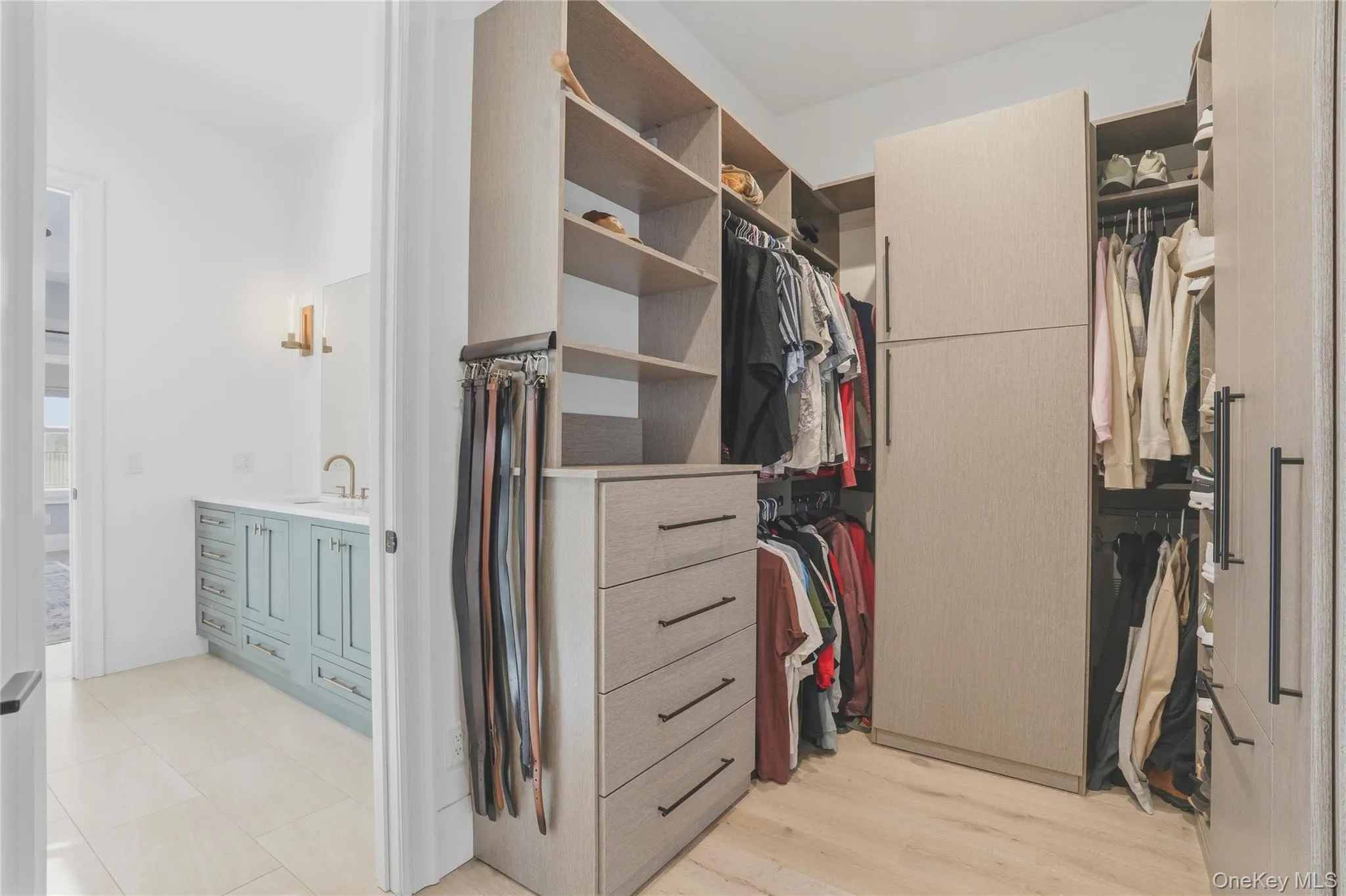 Custom closet system featuring light wood-finish shelving, integrated drawers with dark hardware, and multiple hanging rods Custom closet system featuring light wood-finish shelving, integrated drawers with dark hardware, and multiple hanging rods