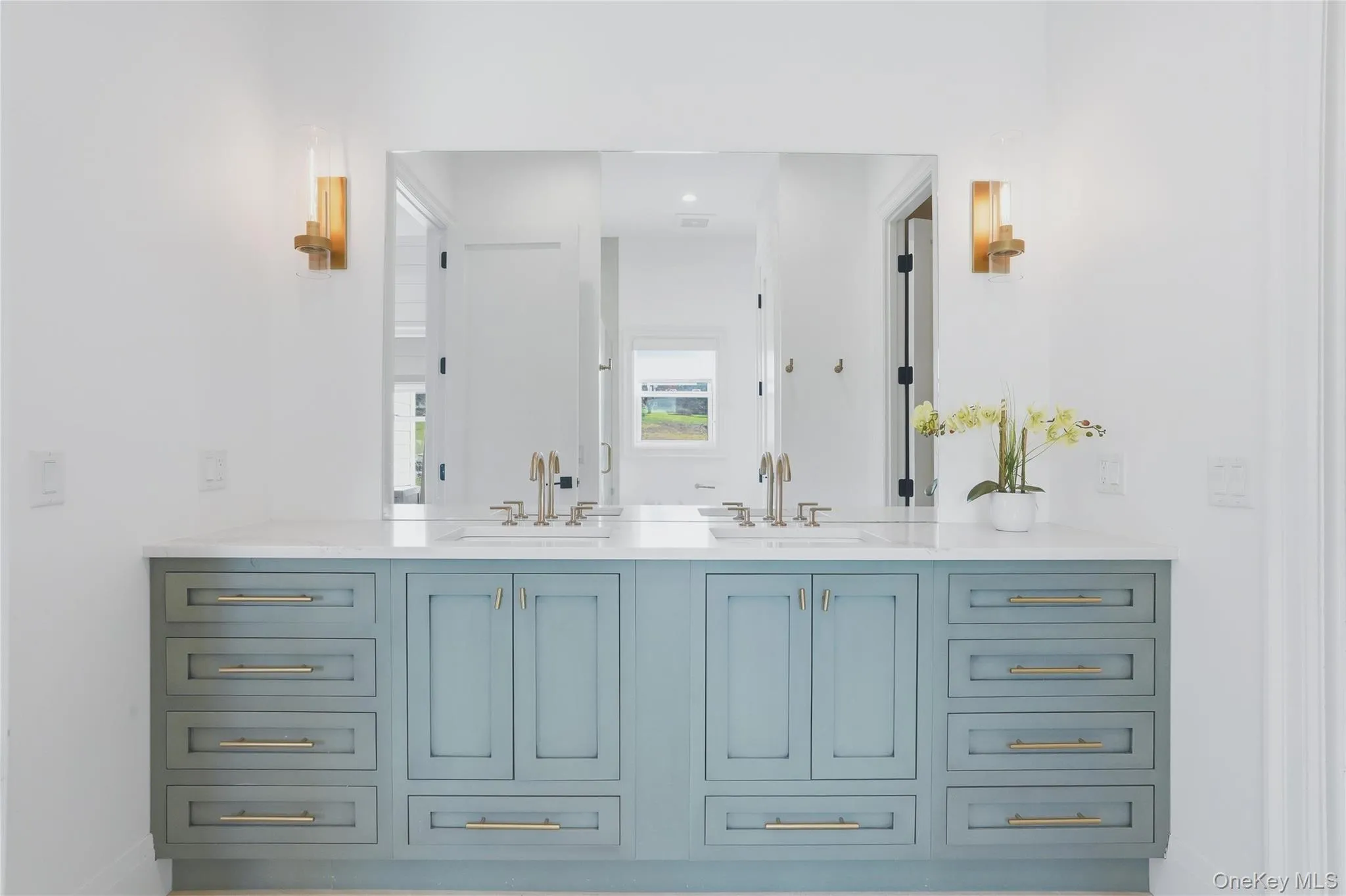 Dual vanity with a white countertop and light blue cabinetry featuring gold-tone hardware Dual vanity with a white countertop and light blue cabinetry featuring gold-tone hardware
