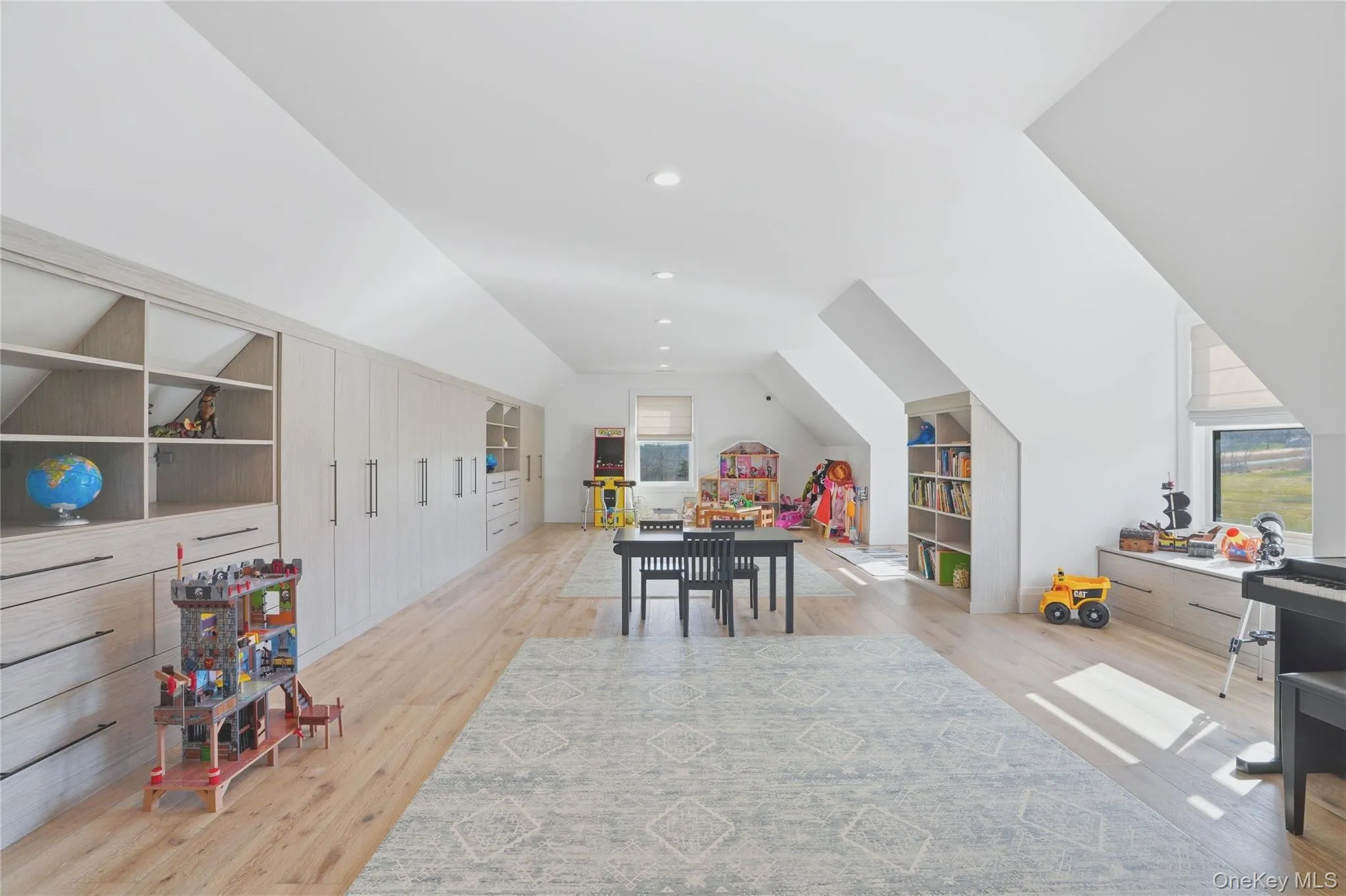 Spacious room featuring wood-finish flooring, recessed lighting, and built-in storage cabinetry Spacious room featuring wood-finish flooring, recessed lighting, and built-in storage cabinetry