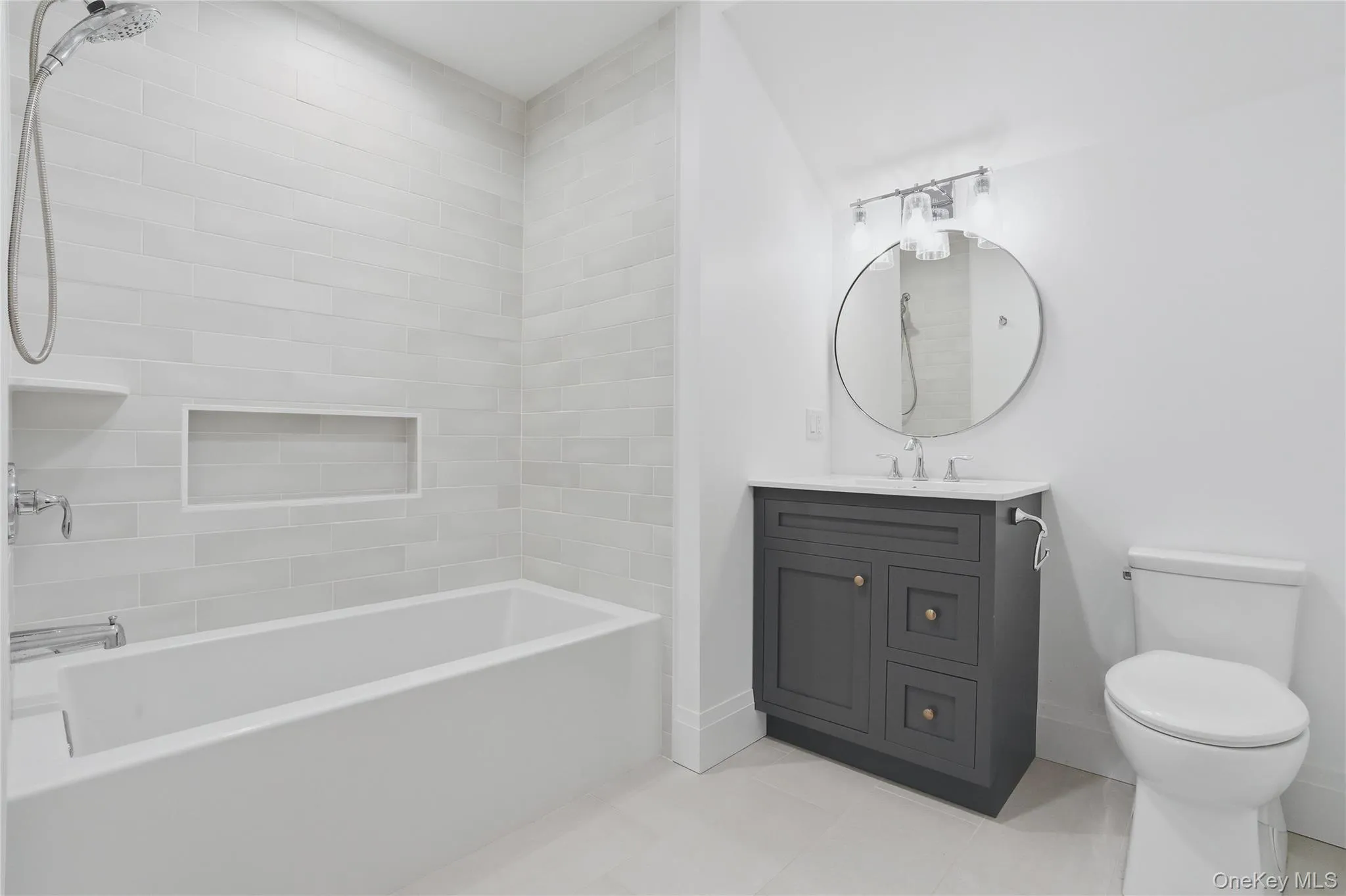 Bathroom featuring a white bathtub with subway tile surround, recessed shower niche, and chrome fixtures Bathroom featuring a white bathtub with subway tile surround, recessed shower niche, and chrome fixtures