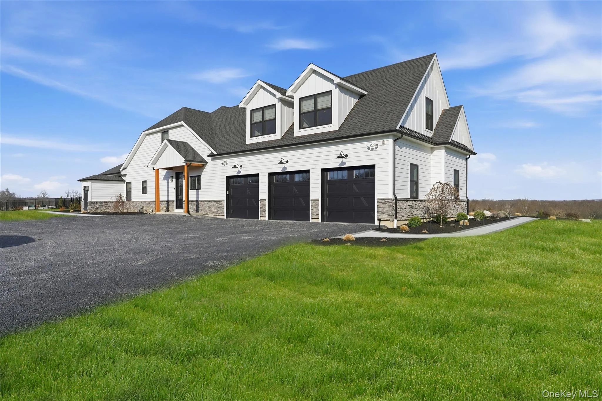 Modern farmhouse-style residence featuring white siding and dark gray stone accents Modern farmhouse-style residence featuring white siding and dark gray stone accents
