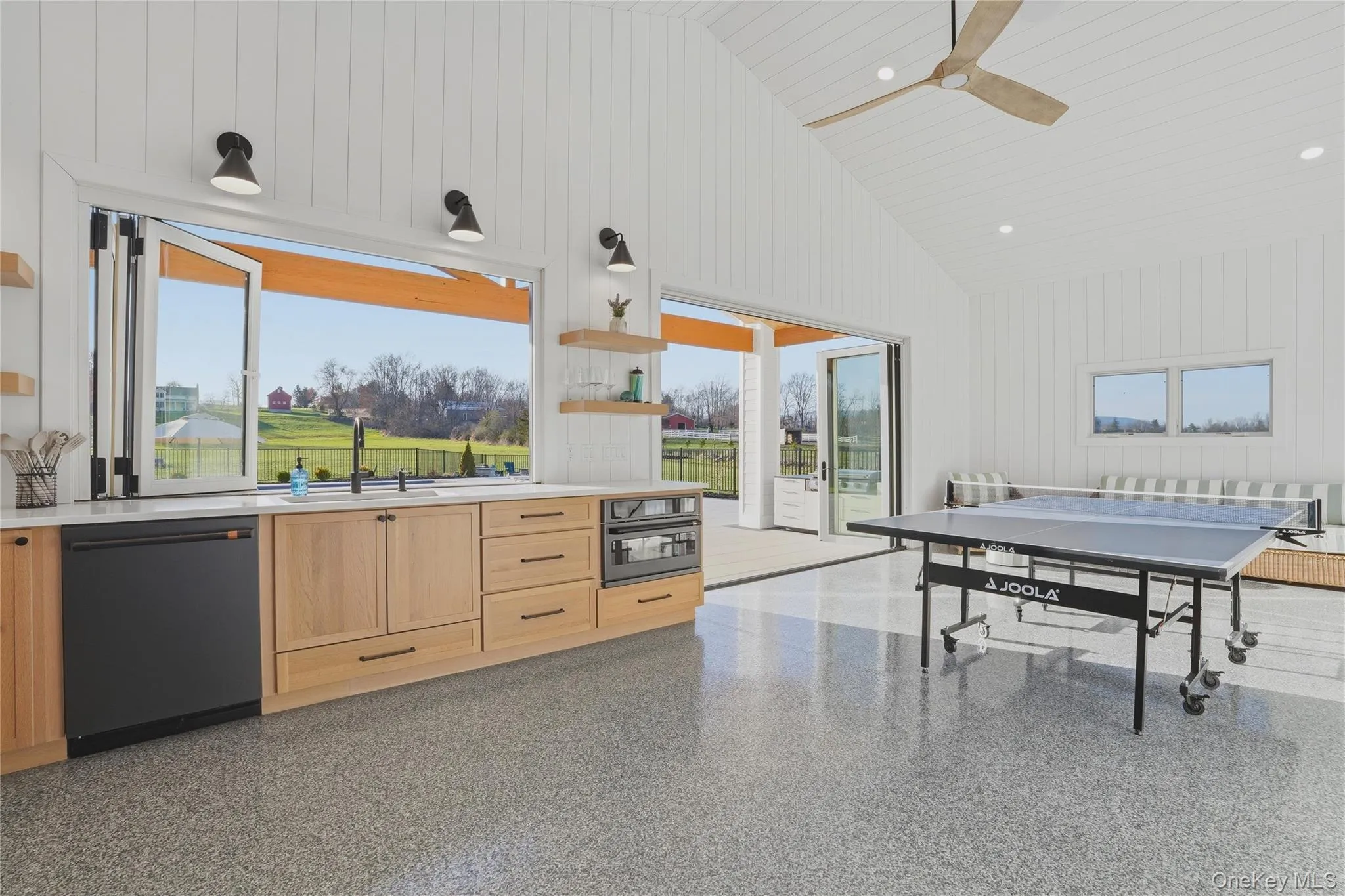 Spacious room featuring vaulted ceilings, shiplap wall finishes, and polished concrete flooring Spacious room featuring vaulted ceilings, shiplap wall finishes, and polished concrete flooring