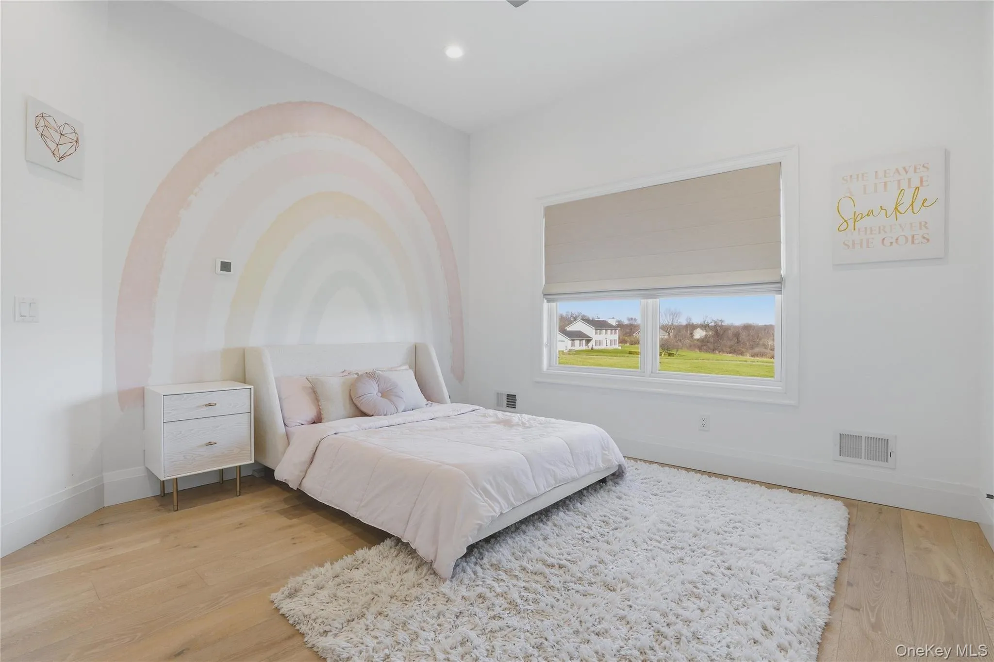 Well-lit interior featuring a broad window, light wood-finish flooring, white walls, and a built-in recessed ceiling light fixture Well-lit interior featuring a broad window, light wood-finish flooring, white walls, and a built-in recessed ceiling light fixture
