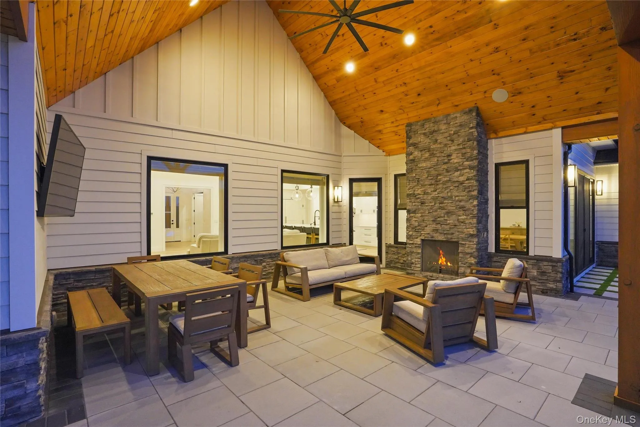 Covered outdoor patio featuring a stone-clad fireplace and wood-finish vaulted ceiling Covered outdoor patio featuring a stone-clad fireplace and wood-finish vaulted ceiling