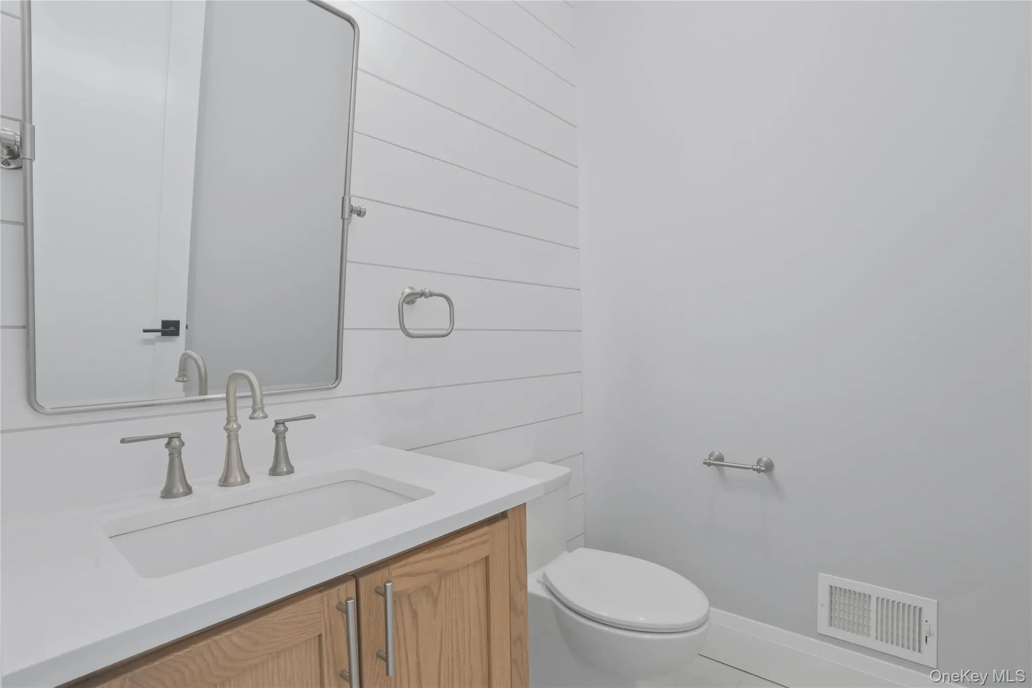 Bathroom vanity with an integrated sink, brushed nickel faucet, and a light wood-finish cabinet Bathroom vanity with an integrated sink, brushed nickel faucet, and a light wood-finish cabinet