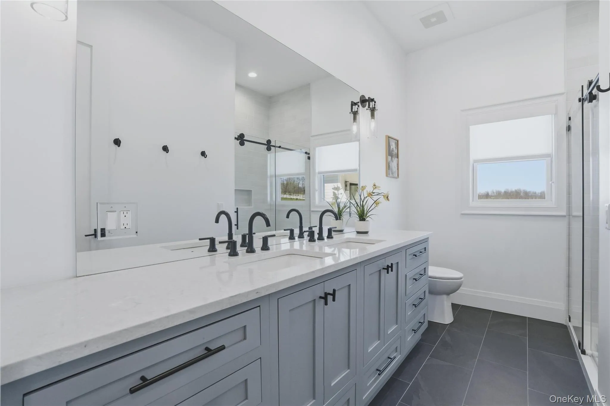 Dual sink vanity featuring light gray cabinetry, white countertop, and matte black fixtures Dual sink vanity featuring light gray cabinetry, white countertop, and matte black fixtures
