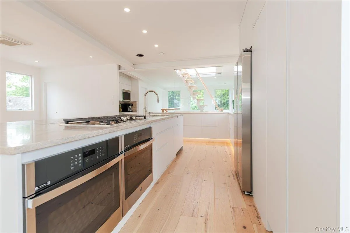 Kitchen with white cabinetry, modern cabinets, light wood-type flooring, recessed lighting, and a spacious island Kitchen with white cabinetry, modern cabinets, light wood-type flooring, recessed lighting, and a spacious island