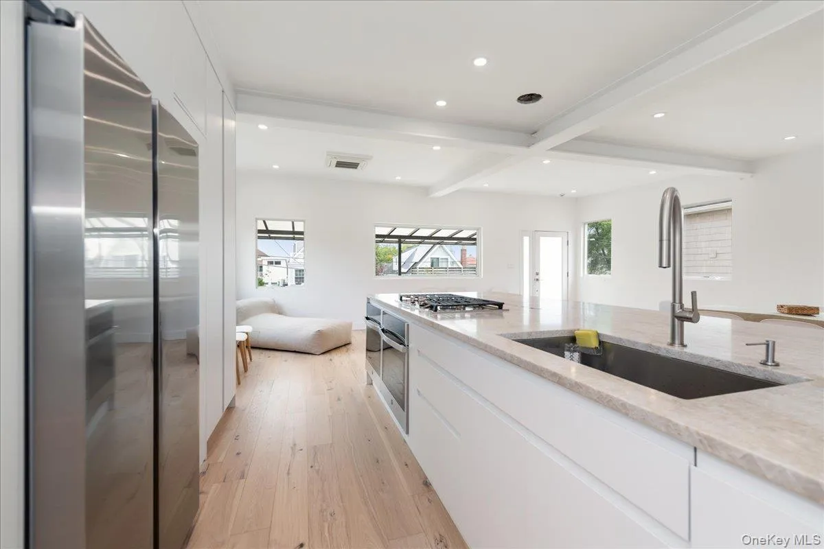 Kitchen with appliances with stainless steel finishes, light wood-style flooring, beamed ceiling, white cabinetry, and recessed lighting Kitchen with appliances with stainless steel finishes, light wood-style flooring, beamed ceiling, white cabinetry, and recessed lighting