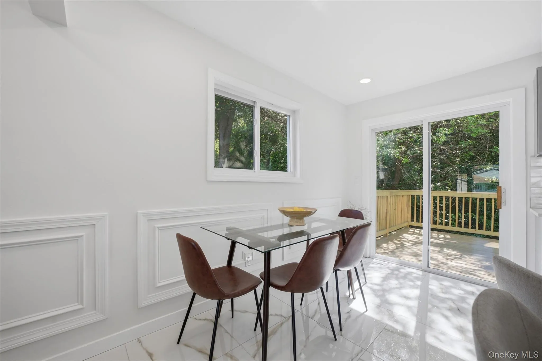 Dining area with white wall paneling and sliding glass doors leading out onto the deck and backyard. Dining area with white wall paneling and sliding glass doors leading out onto the deck and backyard.