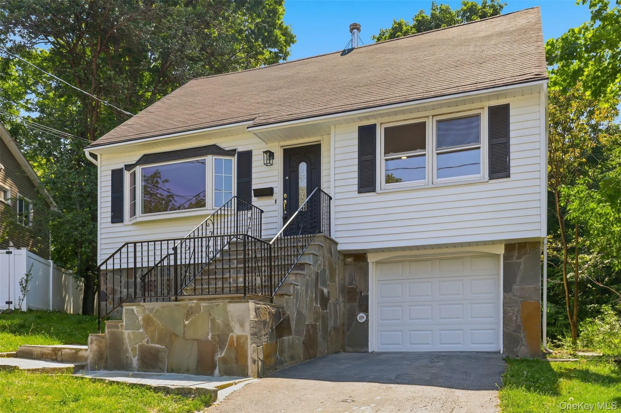 Split-level residence featuring white siding and a brown shingle roof Split-level residence featuring white siding and a brown shingle roof