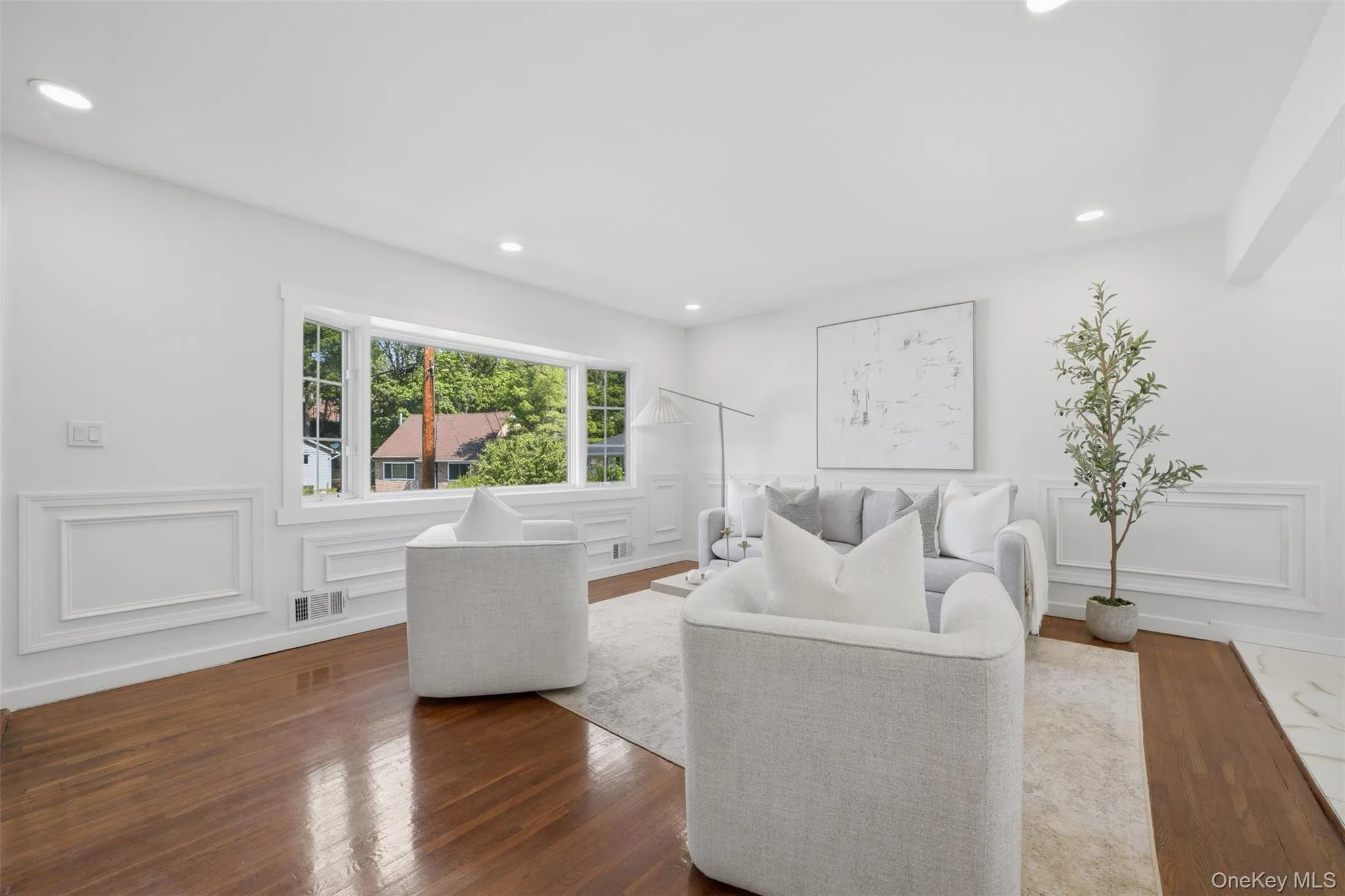 Bright living space featuring a bay window, recessed lighting, and rich wood-finish flooring Bright living space featuring a bay window, recessed lighting, and rich wood-finish flooring
