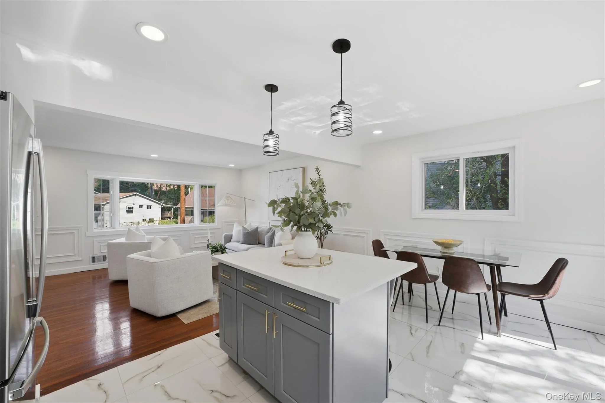 Open-concept living space featuring a central kitchen island with a white countertop and gray cabinetry Open-concept living space featuring a central kitchen island with a white countertop and gray cabinetry