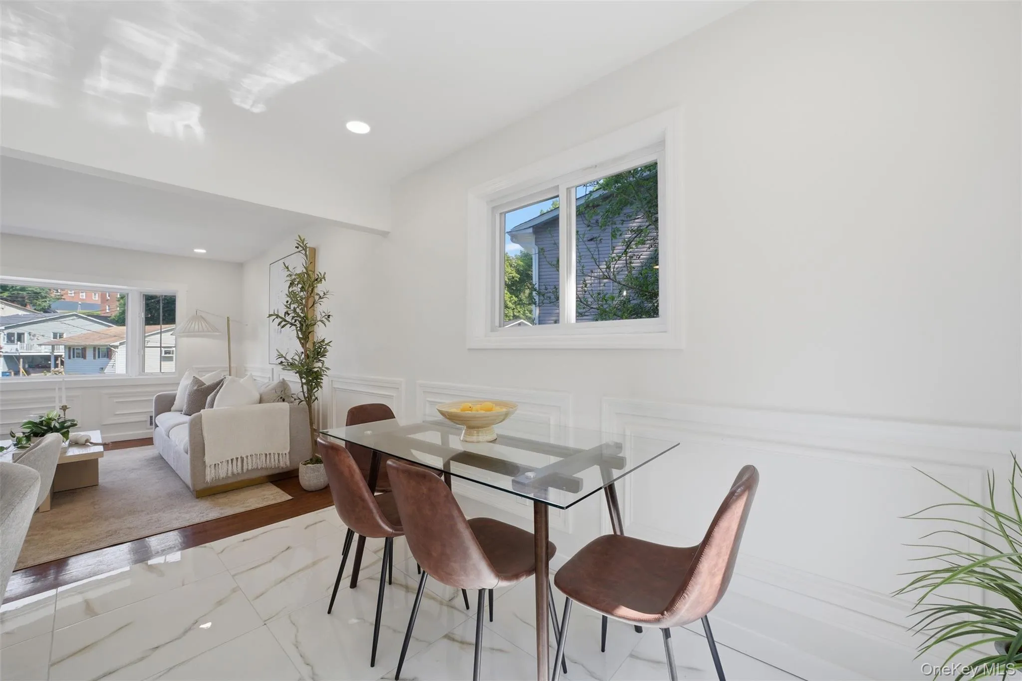 Bright dining area featuring white walls, a single window, and a glass-top dining table Bright dining area featuring white walls, a single window, and a glass-top dining table