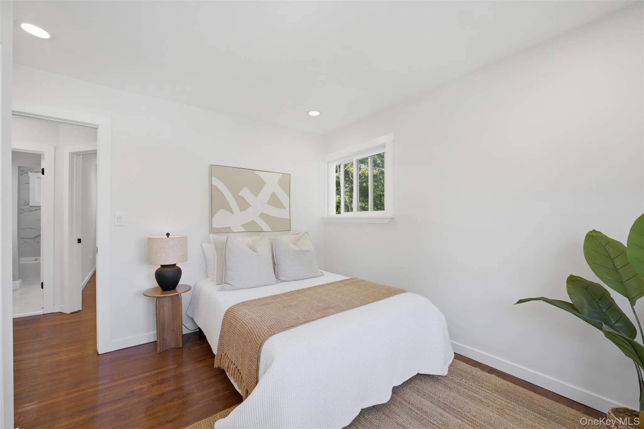 Front bedroom on main floor featuring a white framed window, recessed lighting, and wood-finish flooring Front bedroom on main floor featuring a white framed window, recessed lighting, and wood-finish flooring