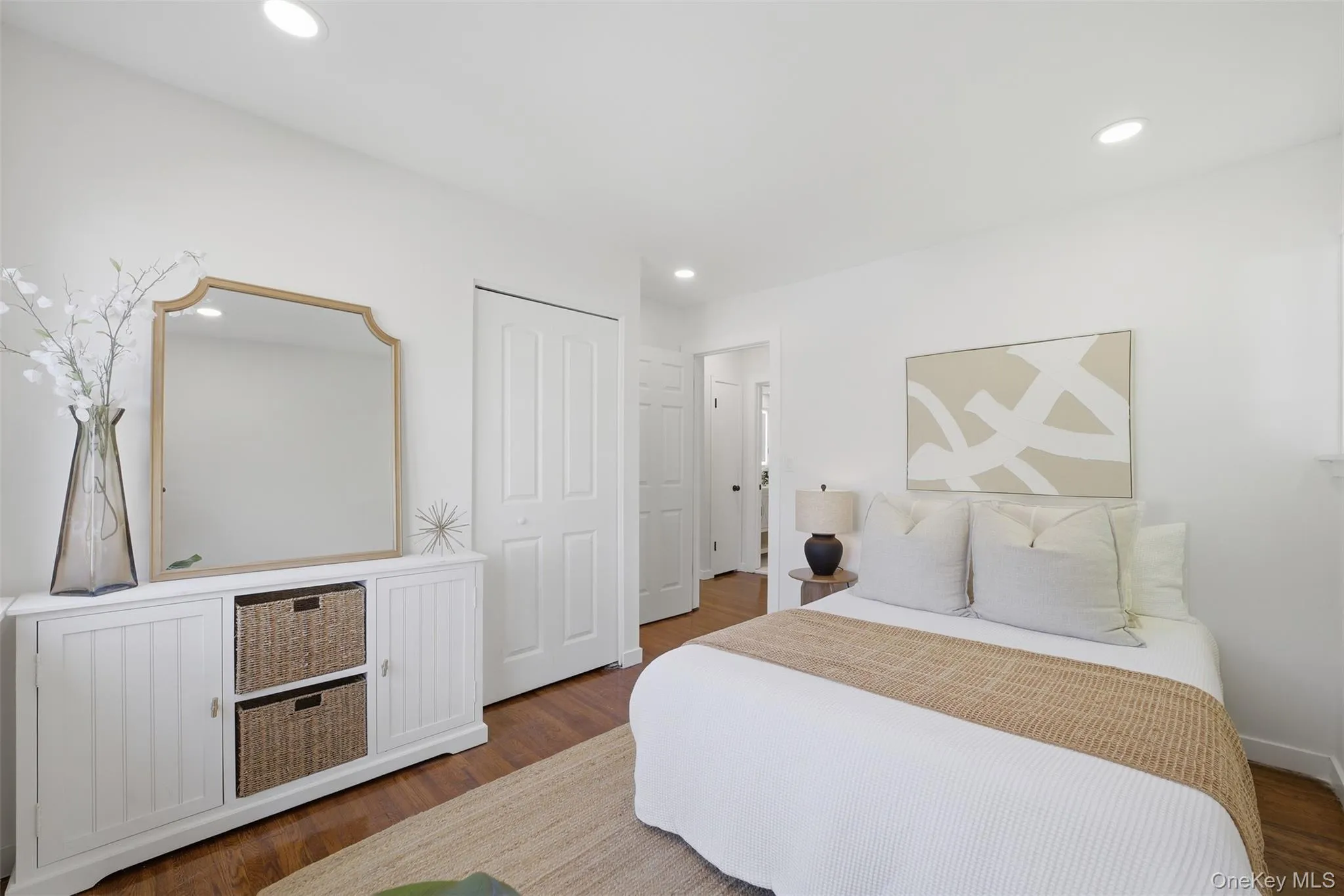 Bright front bedroom on main floor featuring recessed lighting, white walls, wood-finish flooring, and a closet with bifold doors Bright front bedroom on main floor featuring recessed lighting, white walls, wood-finish flooring, and a closet with bifold doors