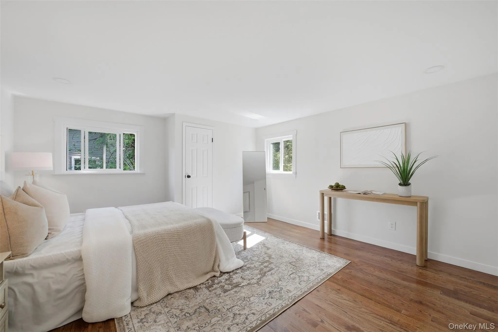 Bright primary bedroom on top floor featuring wood-finish flooring and white walls Bright primary bedroom on top floor featuring wood-finish flooring and white walls