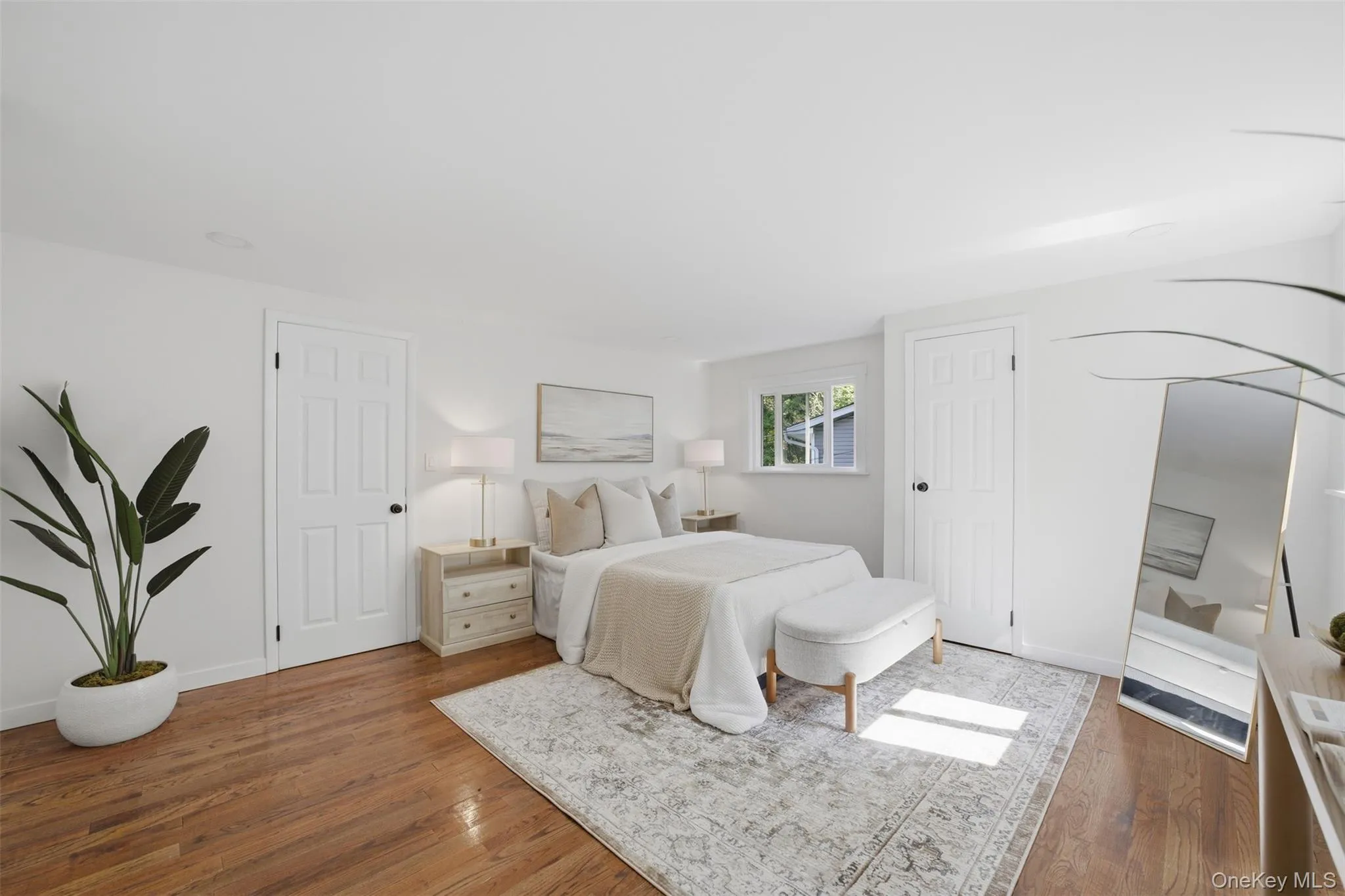 Primary bedroom on top floor featuring wood-finish flooring, white walls, and a window with natural light Primary bedroom on top floor featuring wood-finish flooring, white walls, and a window with natural light