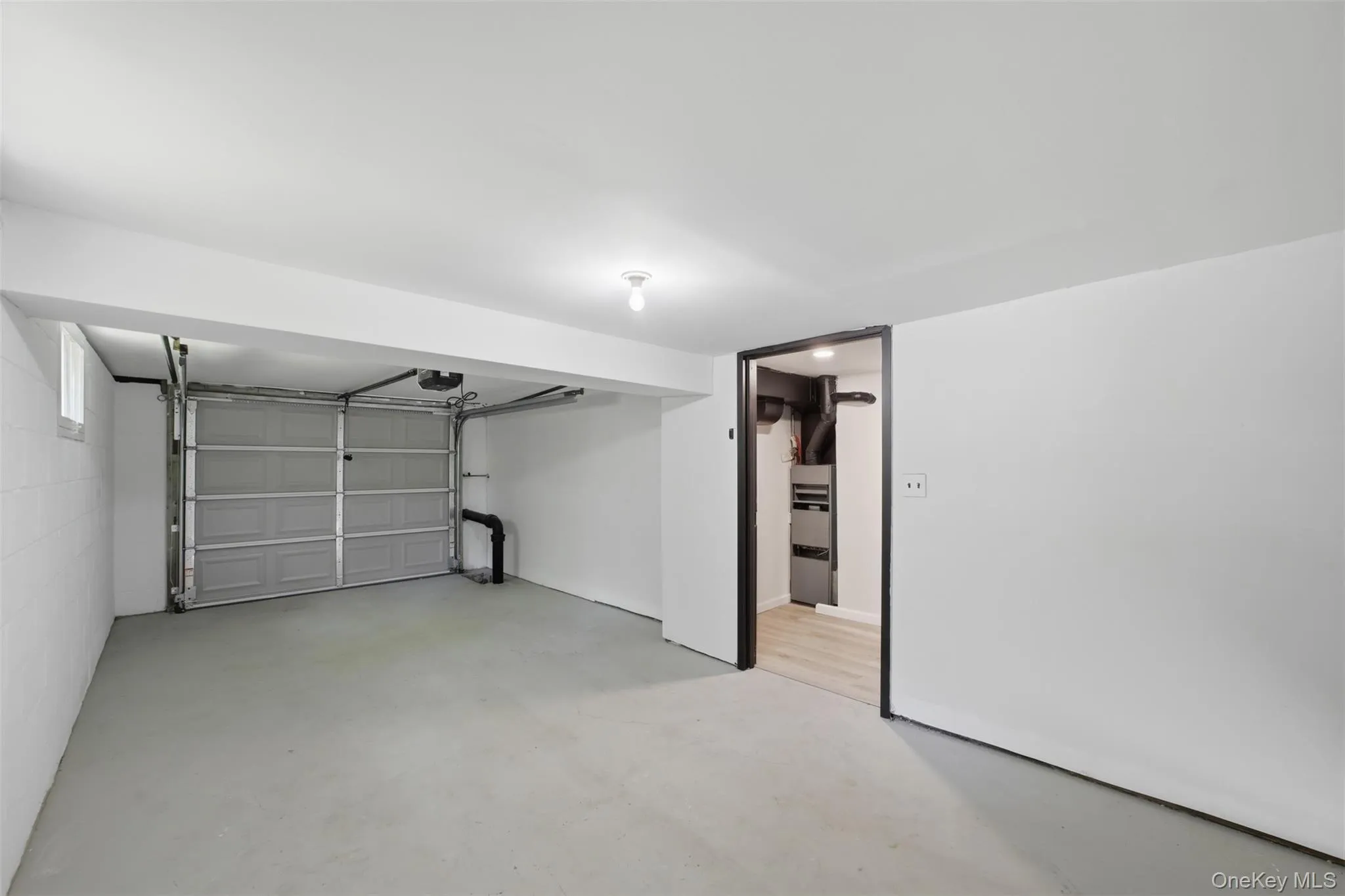 Spacious garage with a gray sectional overhead door, concrete flooring, and white painted walls Spacious garage with a gray sectional overhead door, concrete flooring, and white painted walls