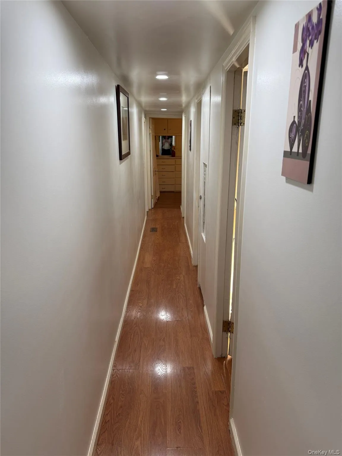 Hallway featuring recessed ceiling lighting and wood-finish flooring Hallway featuring recessed ceiling lighting and wood-finish flooring