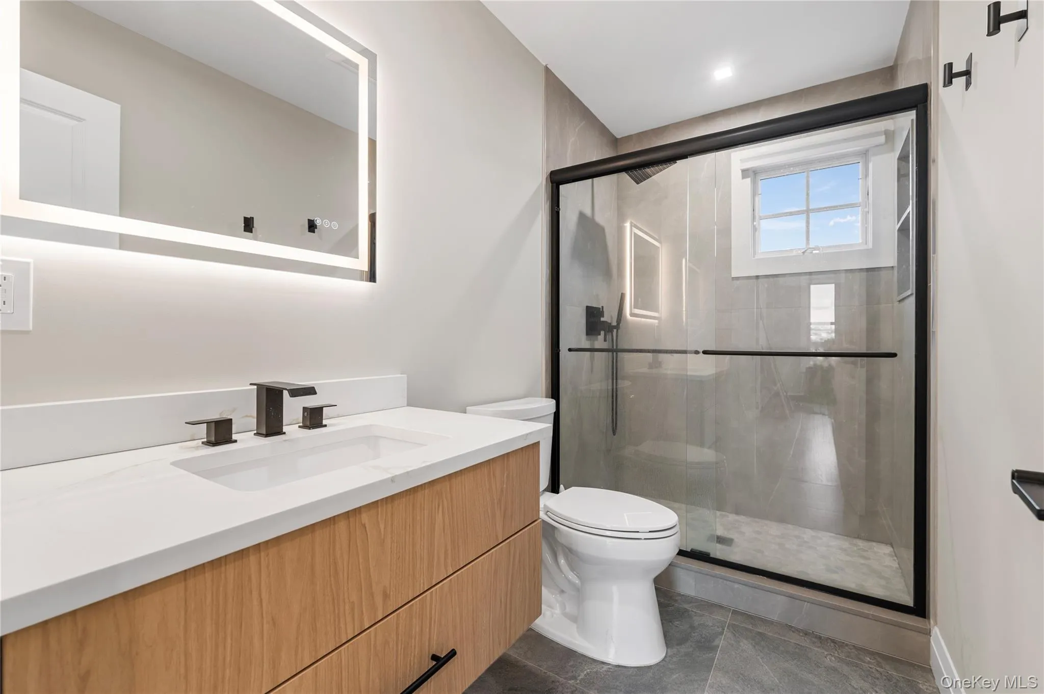 Modern bathroom featuring a wood-finish vanity with a white countertop and rectangular undermount sink Modern bathroom featuring a wood-finish vanity with a white countertop and rectangular undermount sink