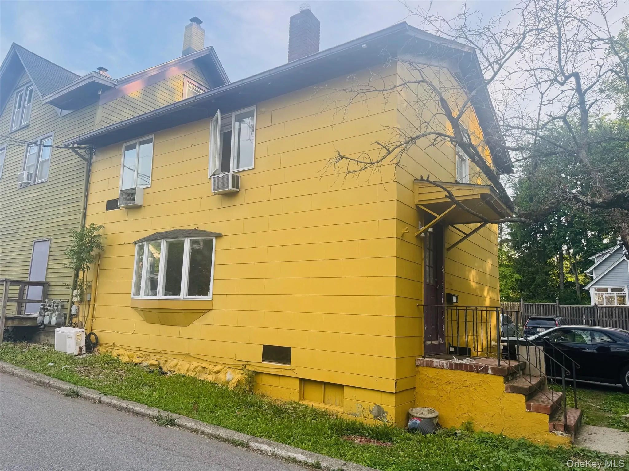 Yellow siding exterior with multiple windows, including a bay window Yellow siding exterior with multiple windows, including a bay window