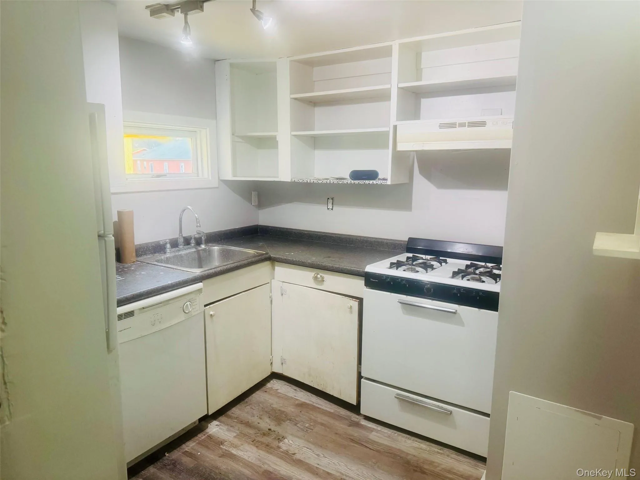 Kitchen featuring wood-finish flooring, a stainless steel sink a white gas range, and open shelving Kitchen featuring wood-finish flooring, a stainless steel sink a white gas range, and open shelving