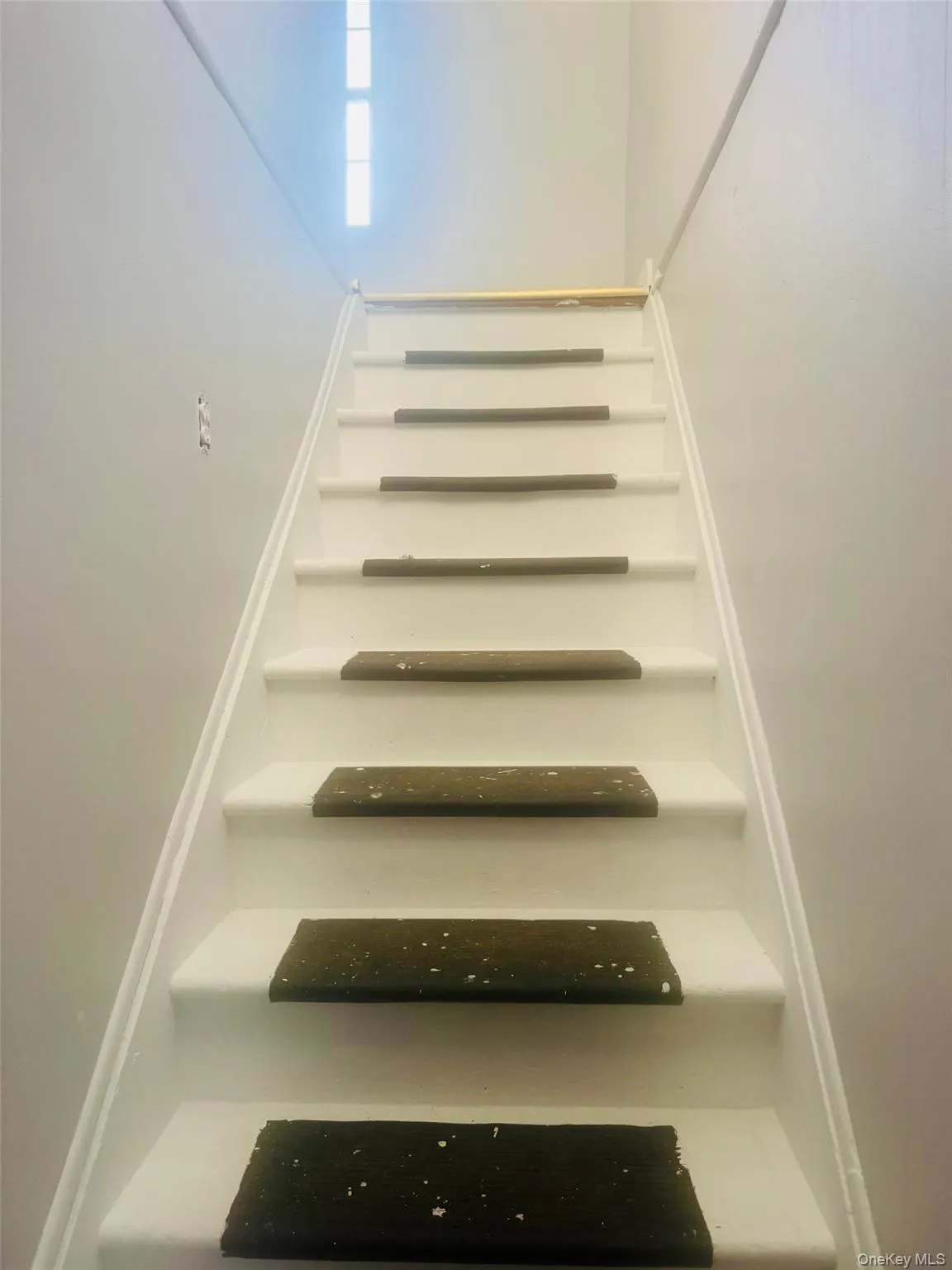 White staircase with dark stair treads and a light-toned wood handrail White staircase with dark stair treads and a light-toned wood handrail