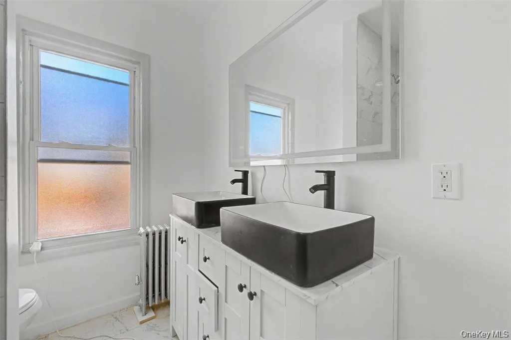 bathroom featuring stunningmarble-style tile, a deepsoaking tub, and dual vesselsinks bathroom featuring stunningmarble-style tile, a deepsoaking tub, and dual vesselsinks