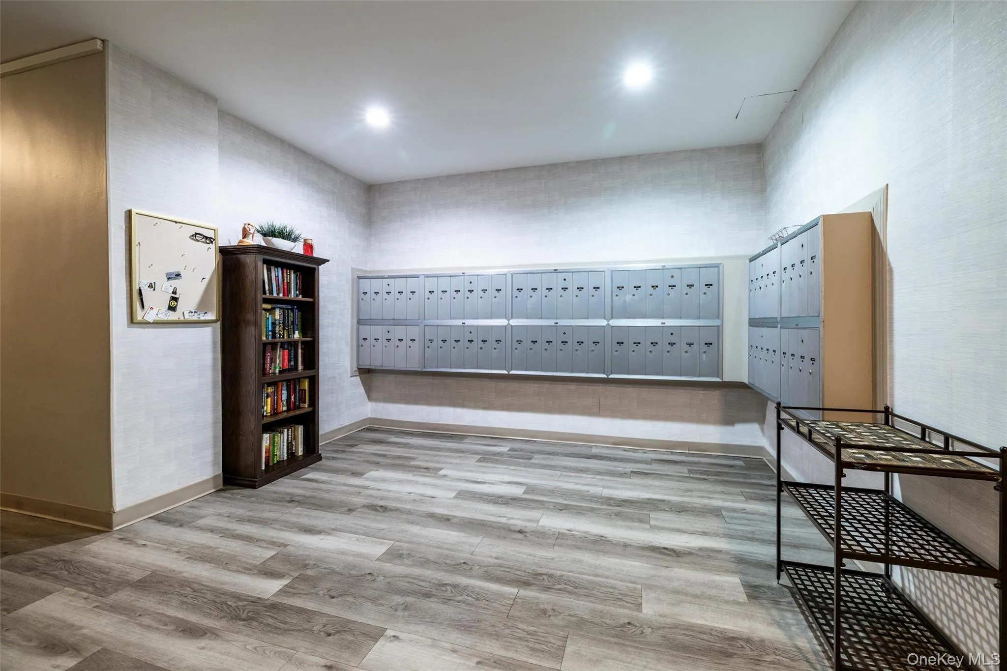 Mailroom featuring multiple banks of secure mailboxes, wood-finish flooring, recessed lighting, and textured wall coverings Mailroom featuring multiple banks of secure mailboxes, wood-finish flooring, recessed lighting, and textured wall coverings