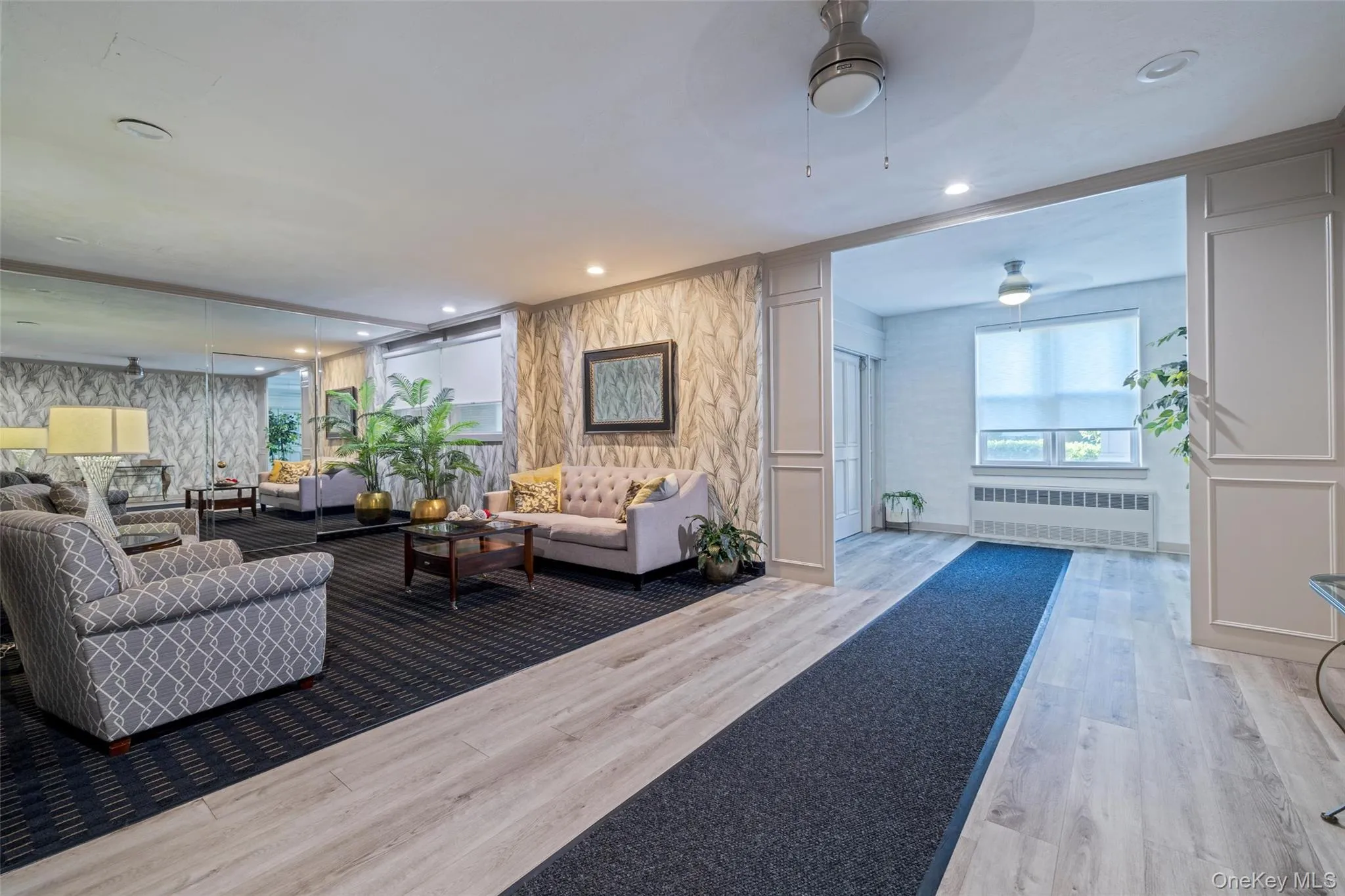Comfortable lobby sitting area featuring wood-finish flooring, a full mirrored wall, and recessed lighting Comfortable lobby sitting area featuring wood-finish flooring, a full mirrored wall, and recessed lighting