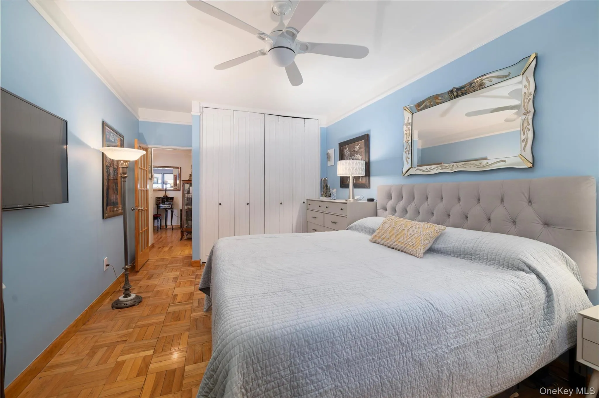 Spacious bedroom featuring parquet wood flooring, crown molding, a ceiling fan, and built-in closet. Spacious bedroom featuring parquet wood flooring, crown molding, a ceiling fan, and built-in closet.