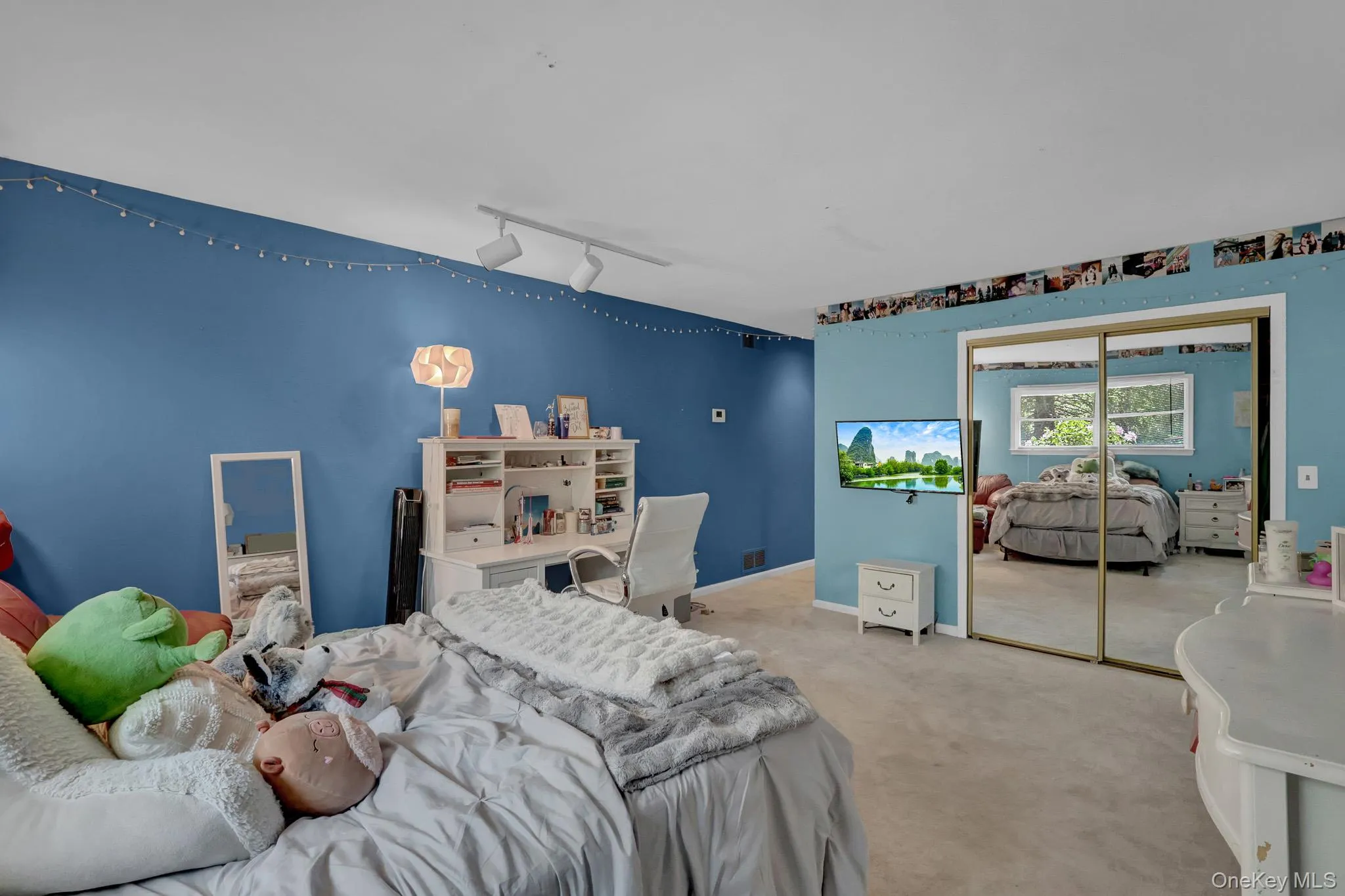 2nd primary Wall-to-wall carpeting throughout this expansive room, featuring a built-in desk unit with shelving, mirrored closet doors, and recessed track lighting 2nd primary Wall-to-wall carpeting throughout this expansive room, featuring a built-in desk unit with shelving, mirrored closet doors, and recessed track lighting