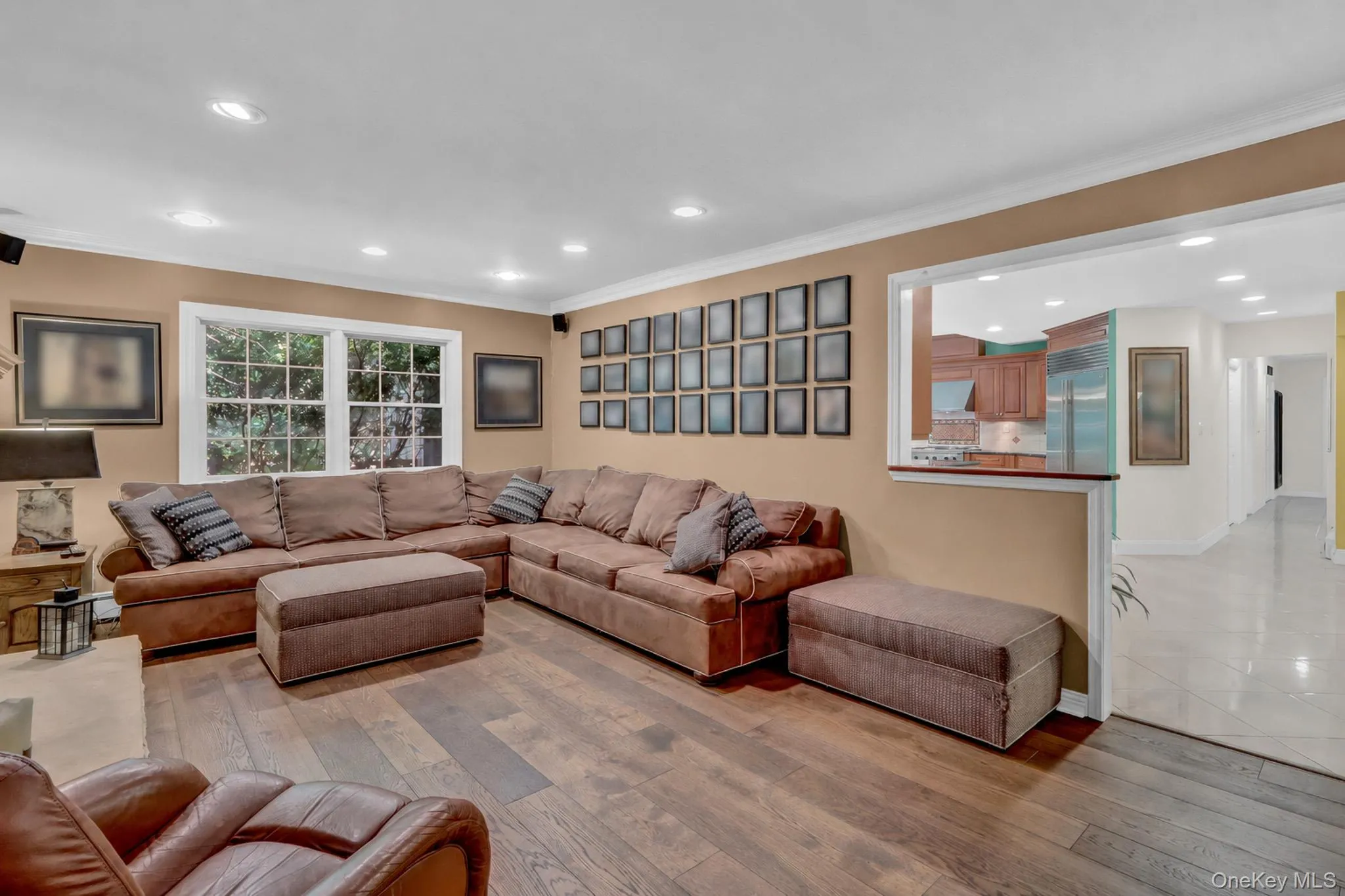 Spacious living area featuring wood-finish flooring, recessed lighting, and a white window frame Spacious living area featuring wood-finish flooring, recessed lighting, and a white window frame