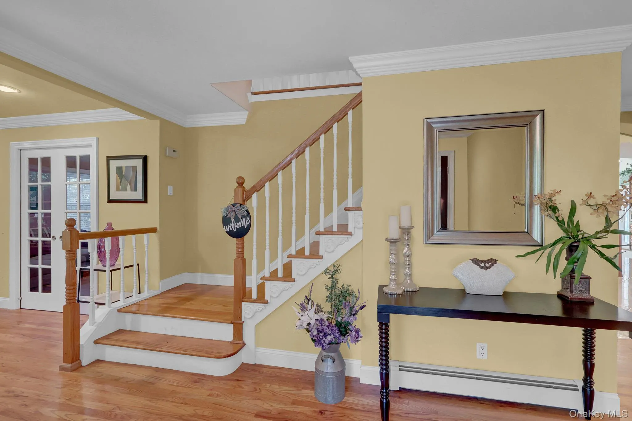Hardwood flooring throughout the entry, a staircase with wood newel posts and handrails, and white balusters Hardwood flooring throughout the entry, a staircase with wood newel posts and handrails, and white balusters