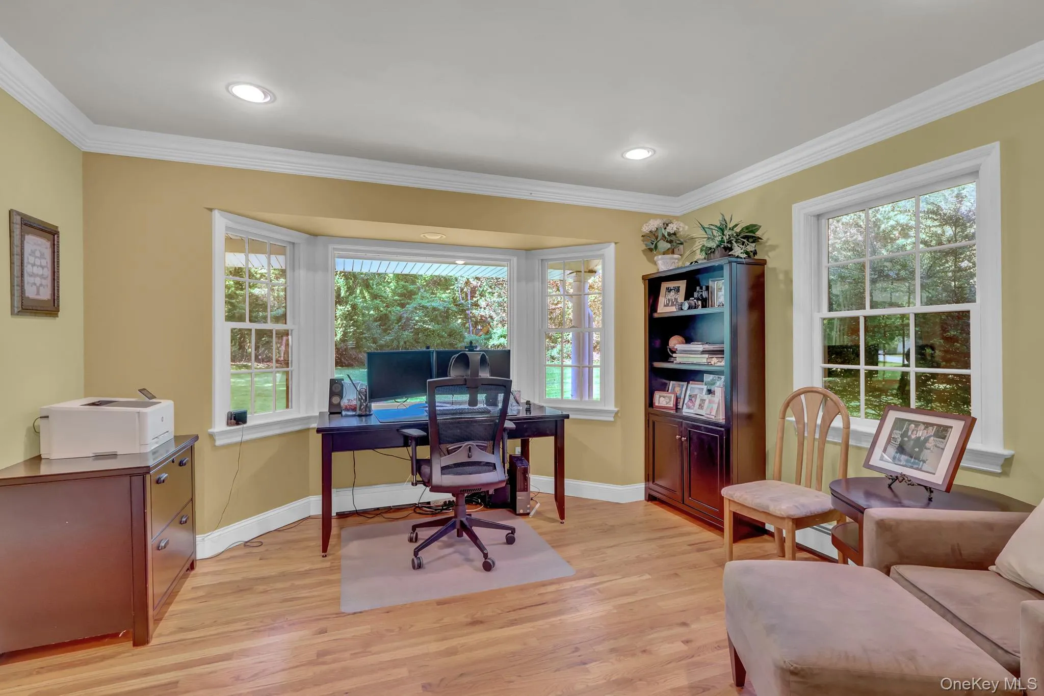 Interior space featuring a prominent bay window, wood-finish flooring, recessed lighting, and white crown molding Interior space featuring a prominent bay window, wood-finish flooring, recessed lighting, and white crown molding