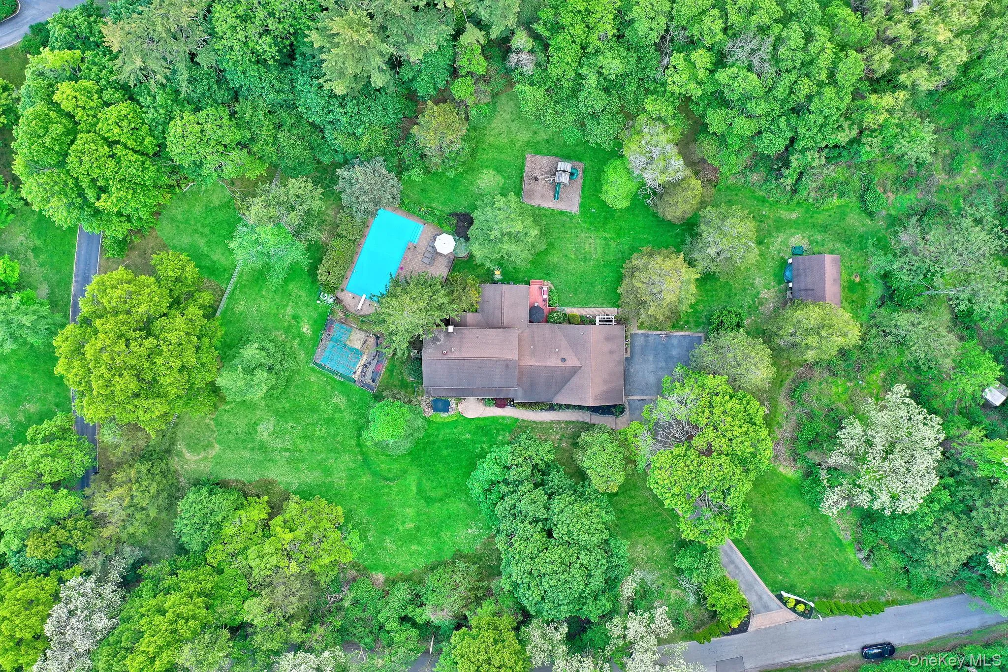 Expansive property featuring a main residence, a detached auxiliary building, a rectangular swimming pool, and a hardscaped patio area Expansive property featuring a main residence, a detached auxiliary building, a rectangular swimming pool, and a hardscaped patio area