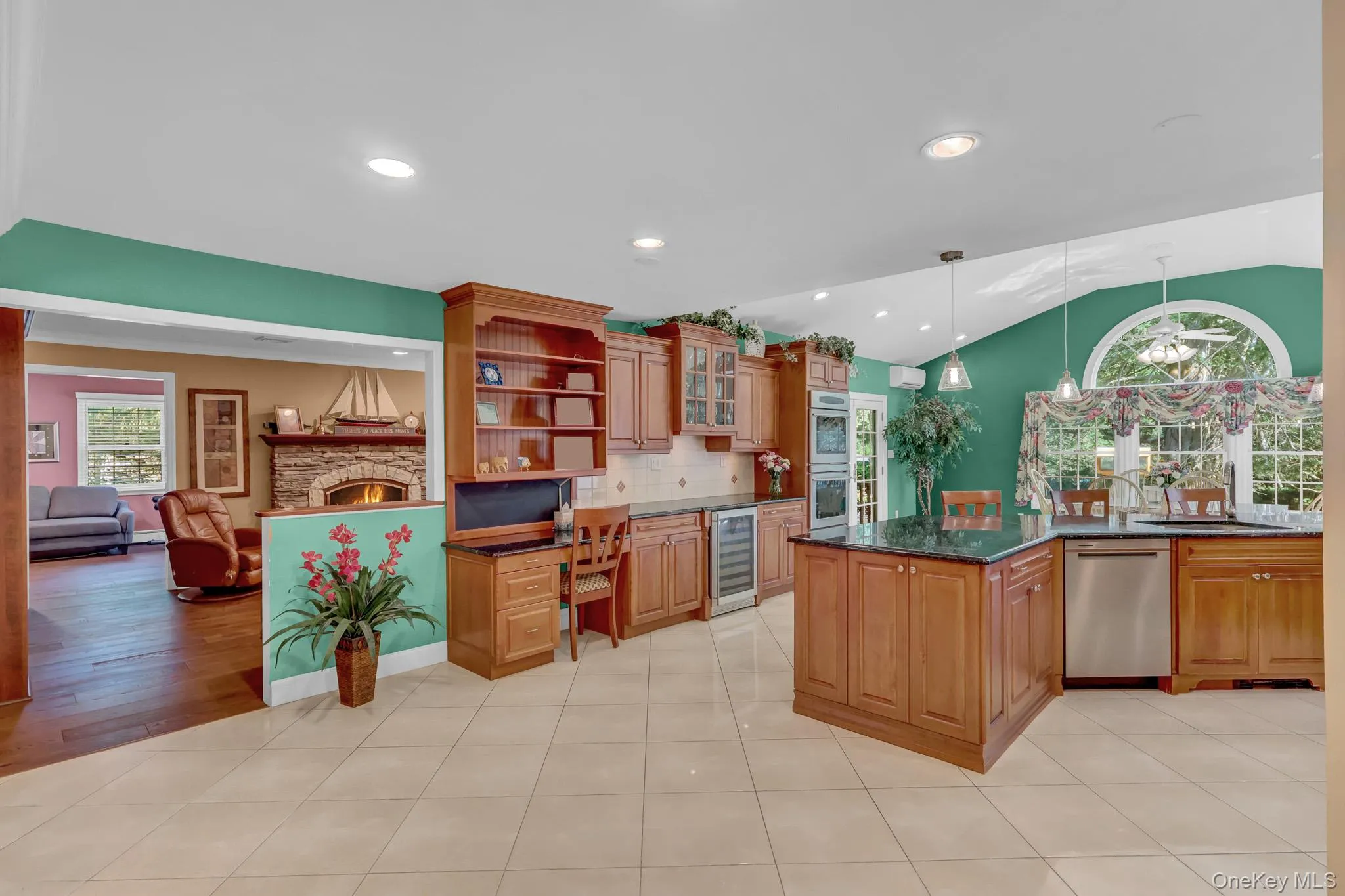 Kitchen featuring tile flooring, wood cabinetry, built-in double ovens, a center island with a dark countertop, and a built-in wine refrigerator Kitchen featuring tile flooring, wood cabinetry, built-in double ovens, a center island with a dark countertop, and a built-in wine refrigerator